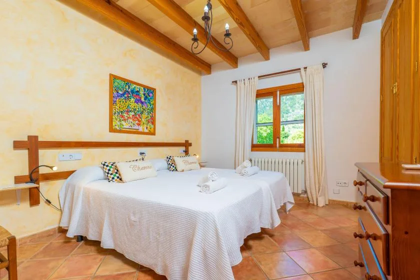 A bedroom with a double bed beneath exposed wooden ceiling beams.