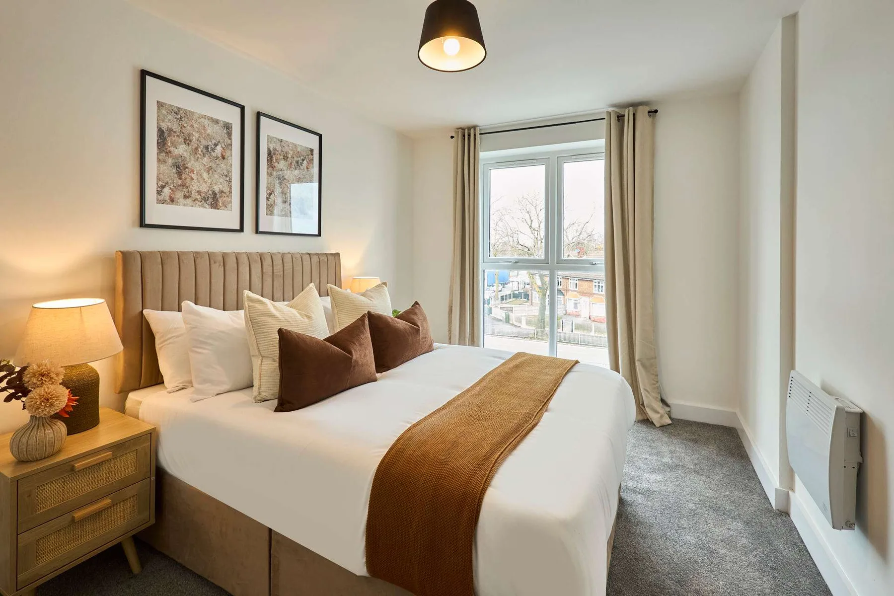A bedroom with a neatly made bed beside a large window.