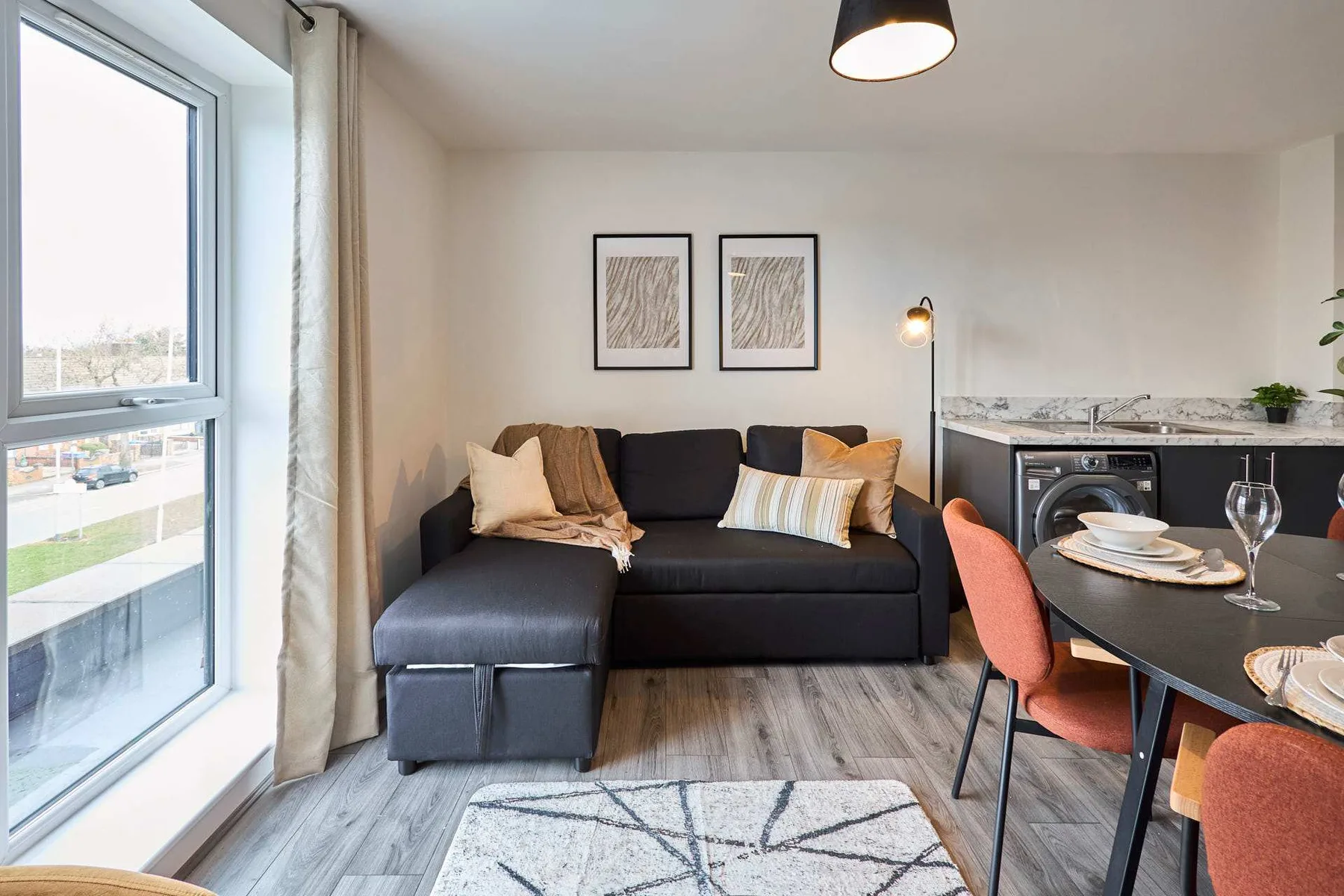 A living and dining area with a dark sectional, table, and large window.