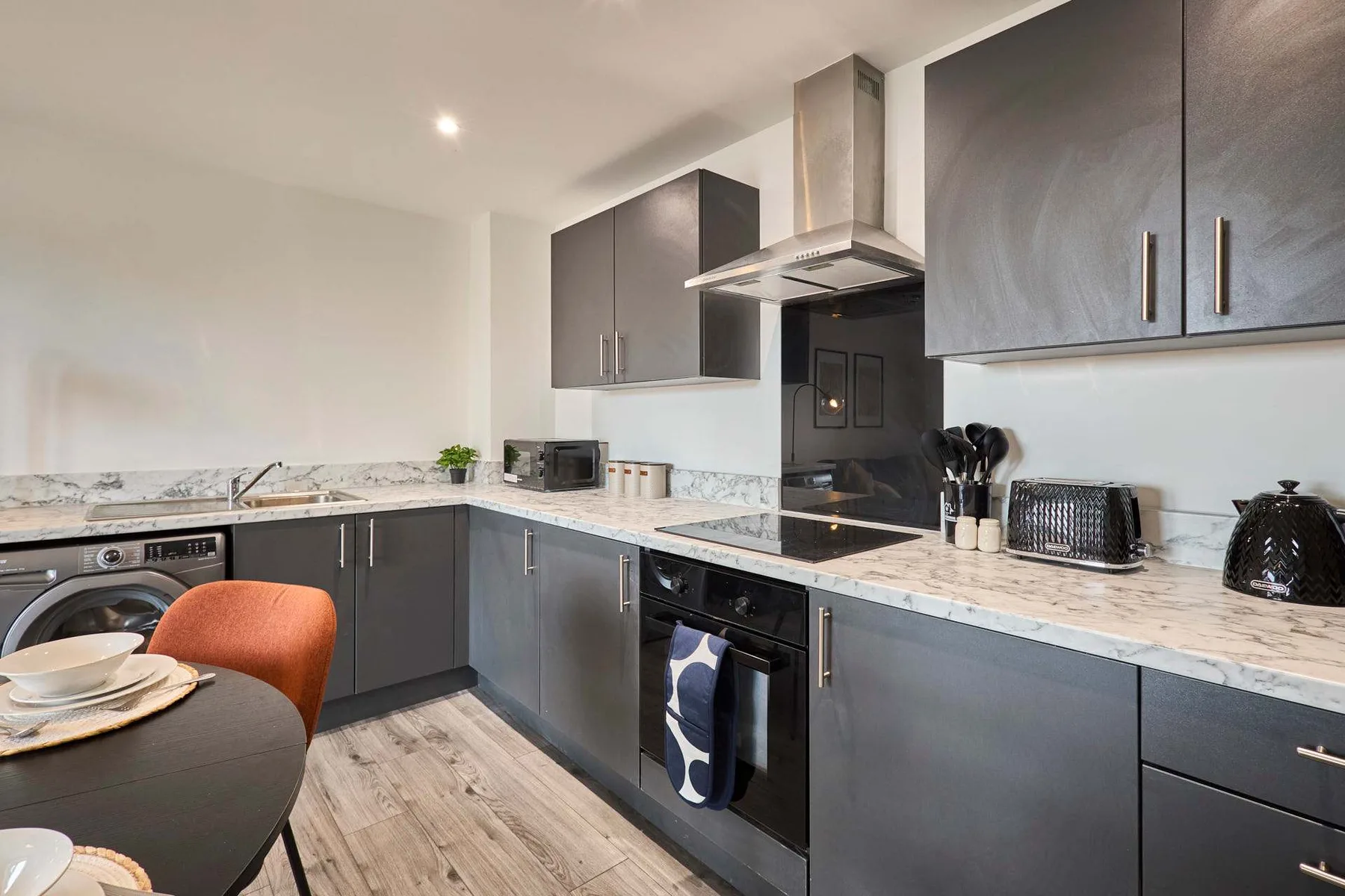 Modern kitchen with dark cabinets, marble-patterned counters, and a central cooking area.