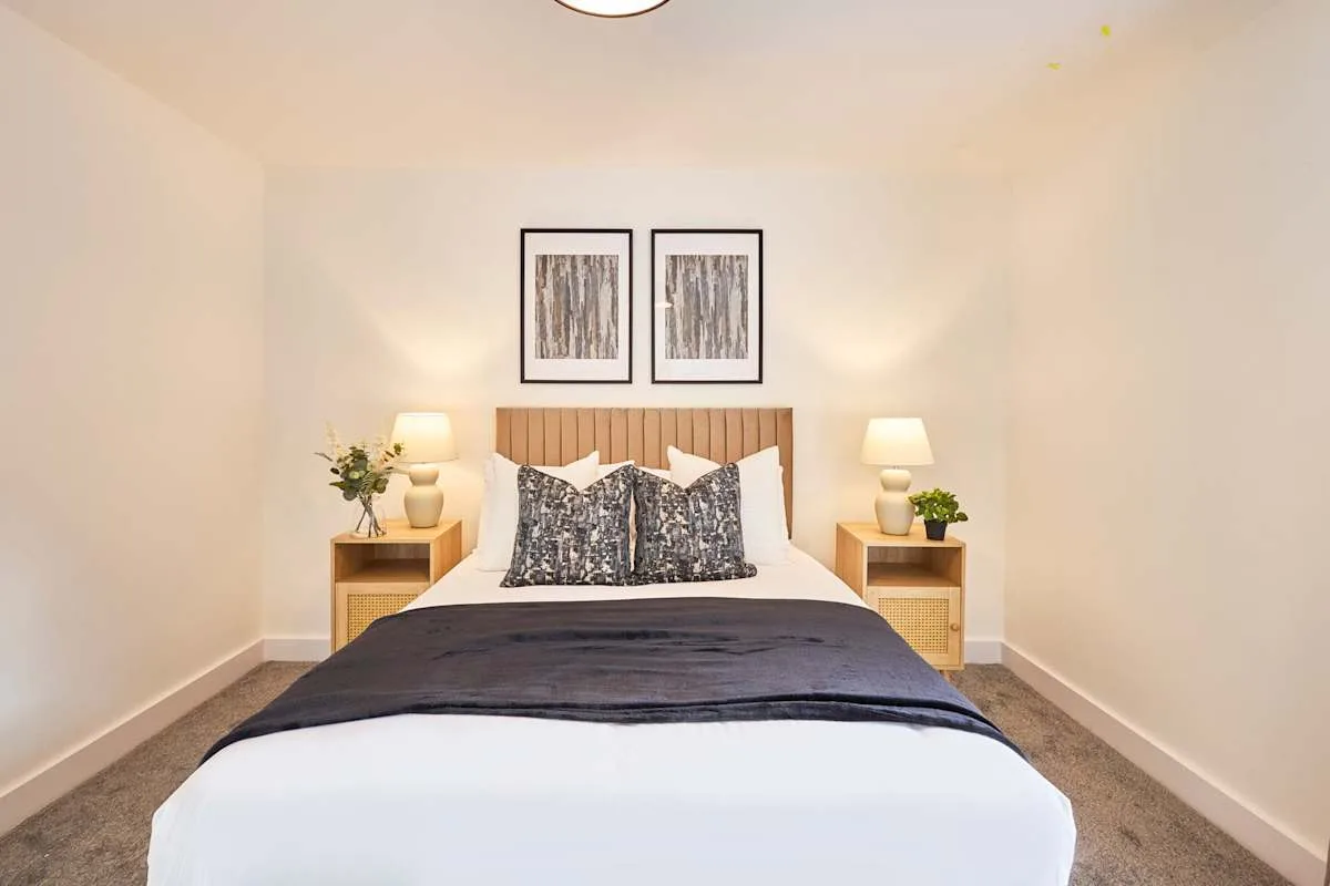 A bedroom with a neatly made bed and framed artwork above the headboard.