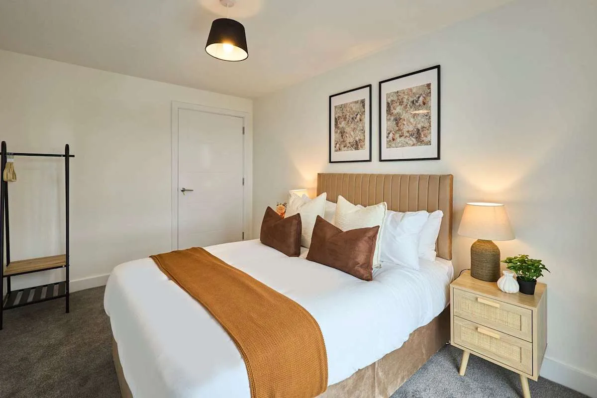 A bedroom with a neatly made bed and framed artwork above the headboard.