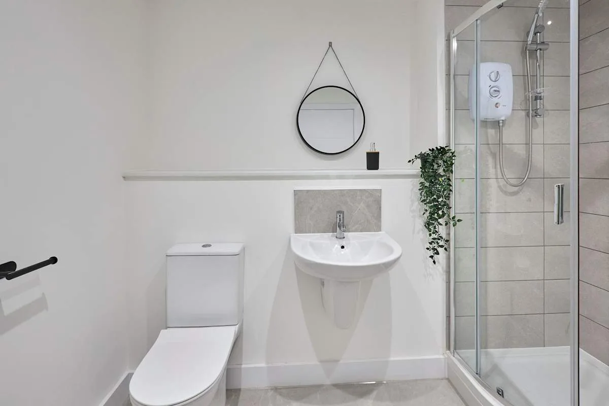 A bathroom with a wall-mounted sink, toilet, and glass shower.