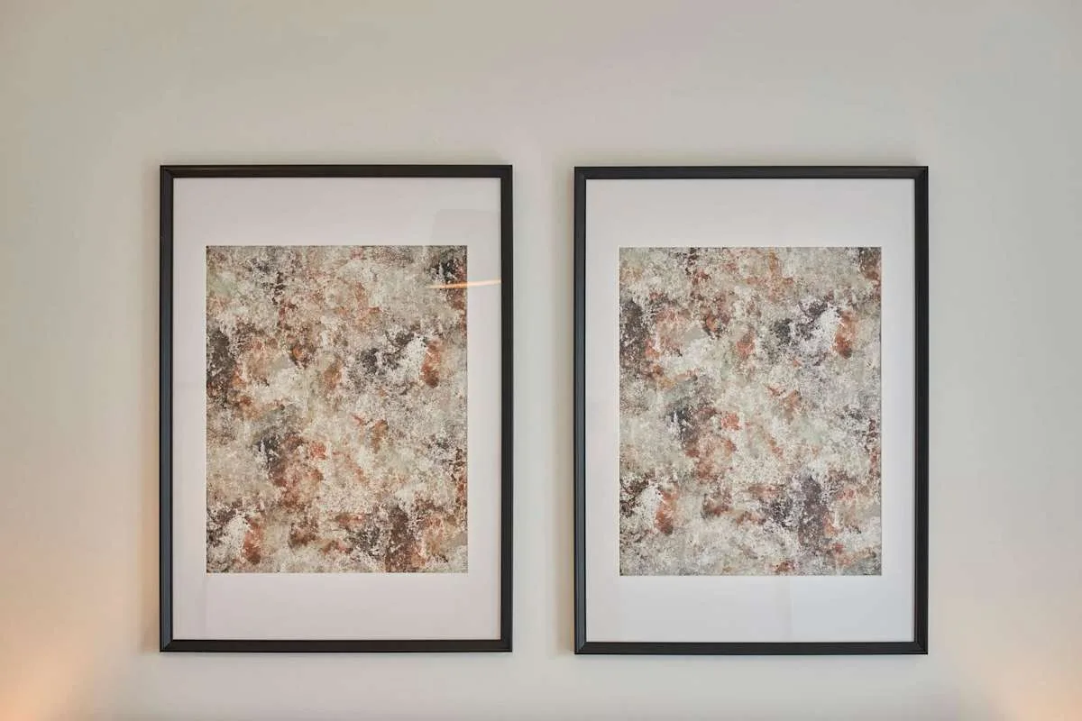 Two framed abstract artworks hang side by side on a light-colored wall.