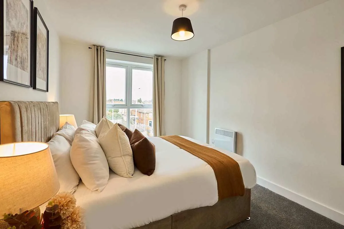 A bedroom with a neatly made bed and a window with curtains.