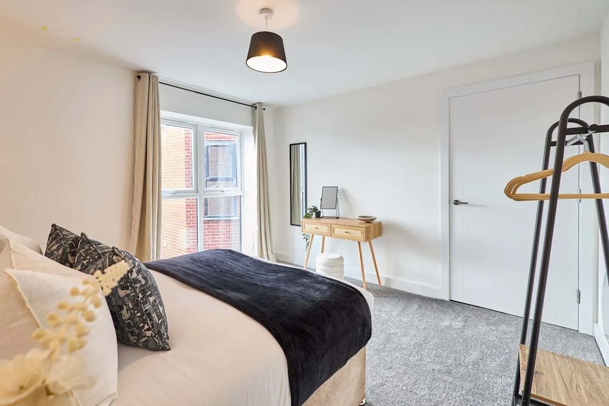 A bedroom with a bed, window, and small desk.