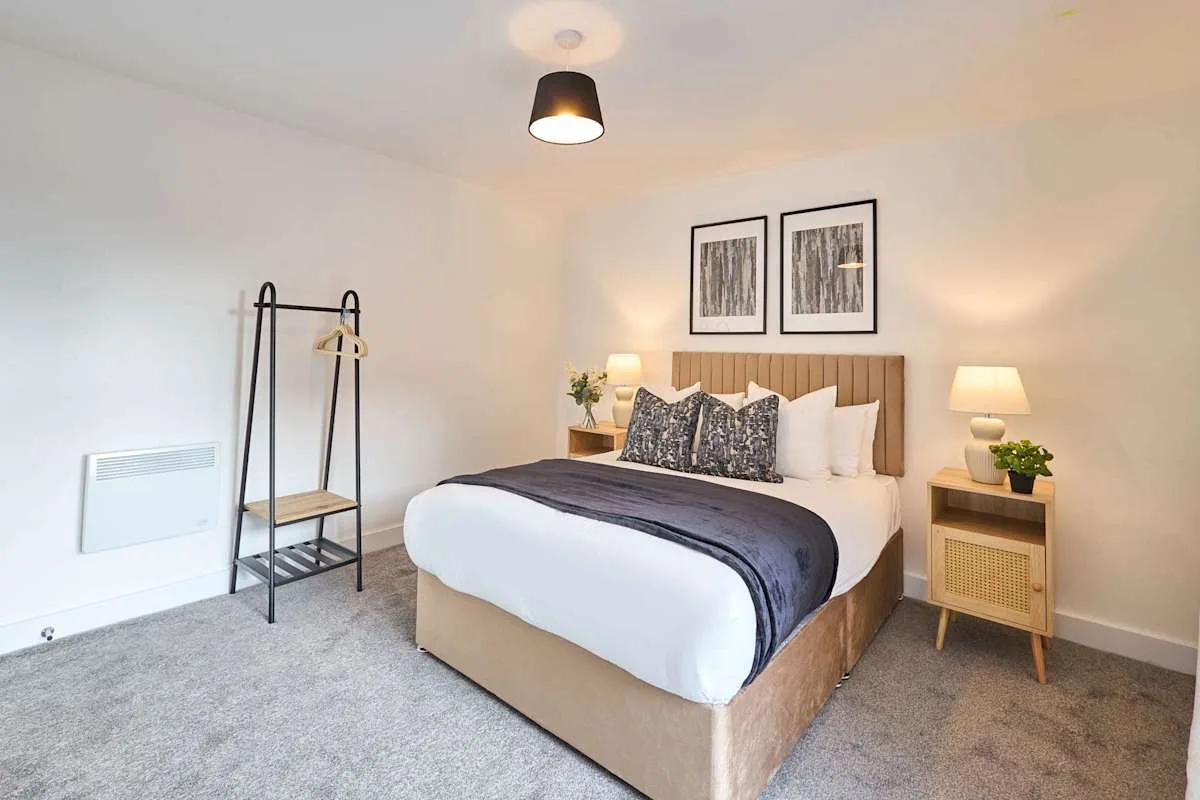 A bright bedroom with a neatly made bed and matching bedside tables.