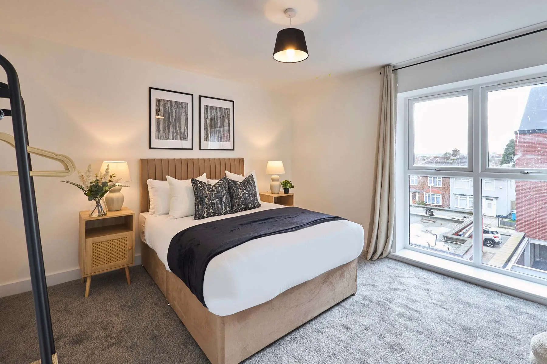 A bedroom with a bed, bedside tables, and a large window.