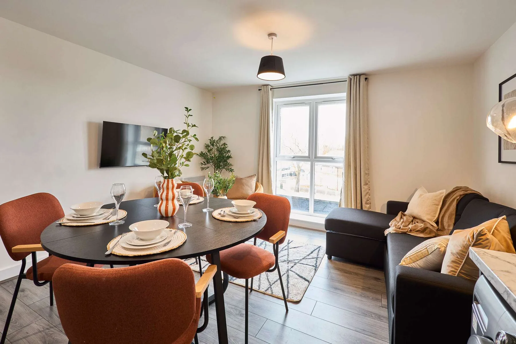 A bright living and dining area with a table, seating, and a window.