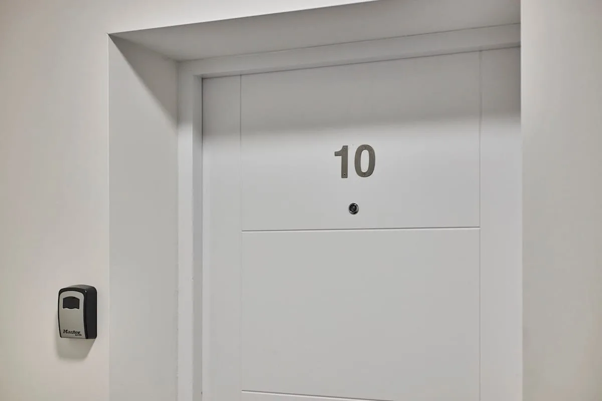 A white entry door with the number 10 and a wall-mounted keypad.