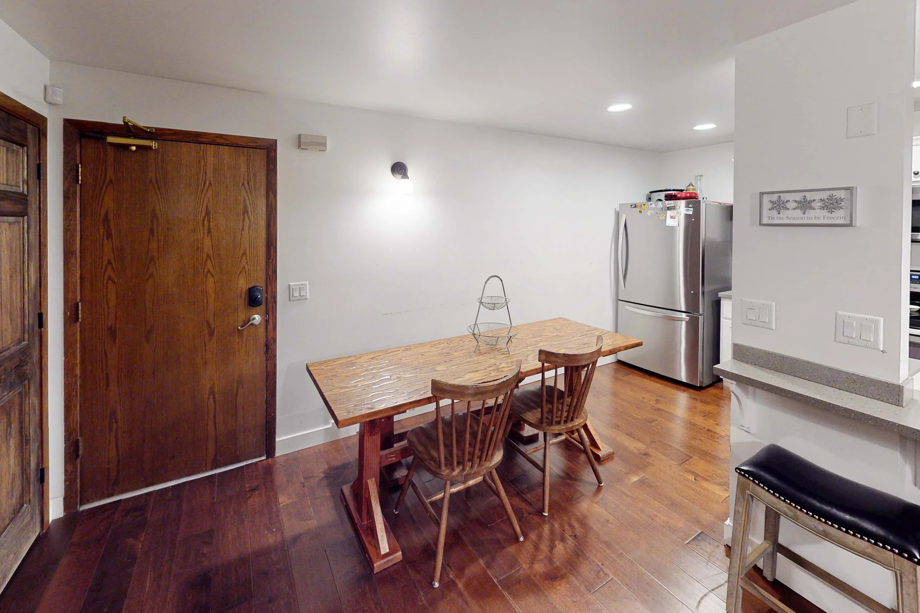 Un comedor con una mesa de madera y asientos junto a un refrigerador.