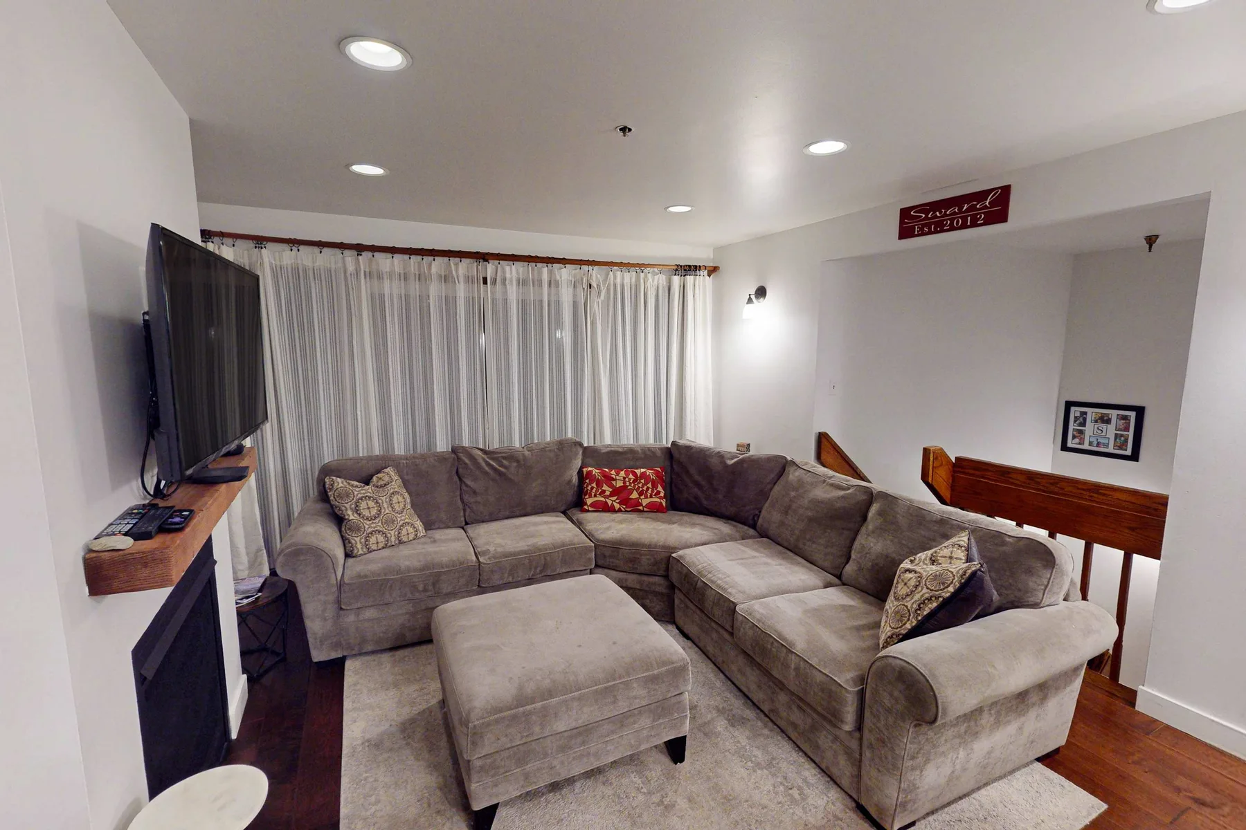 Una sala de estar con un amplio sofá seccional y un televisor.