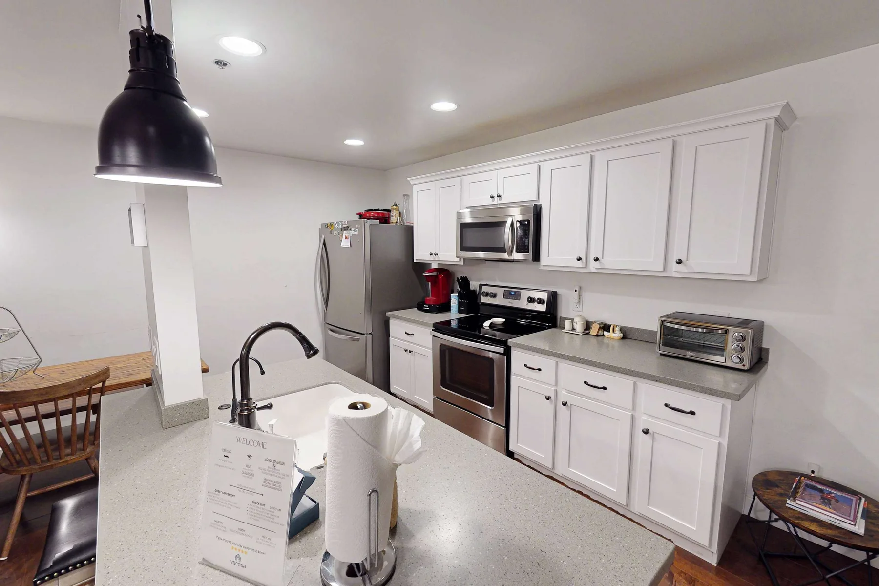 Una cocina luminosa con gabinetes blancos, electrodomésticos de acero inoxidable y una amplia encimera.
