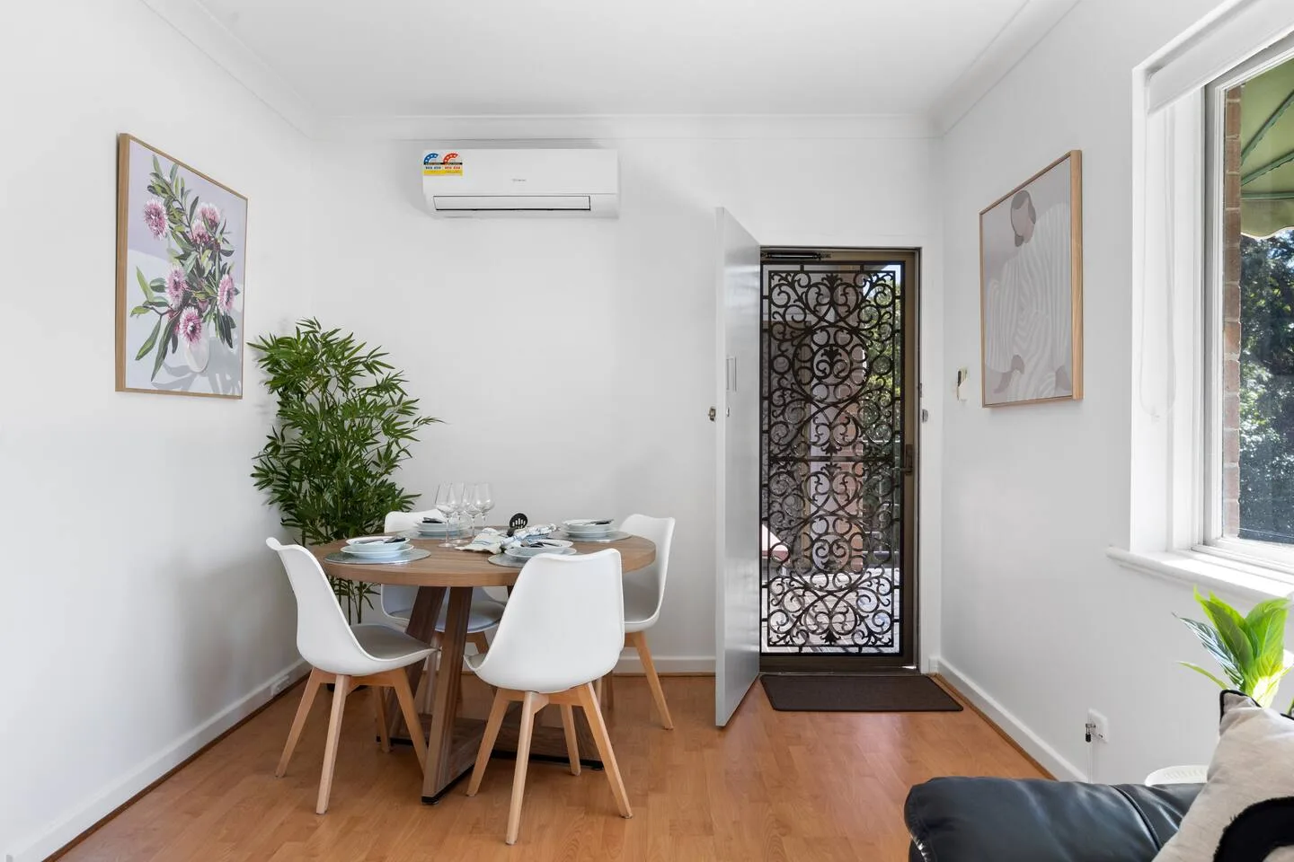 A bright dining area with a set table and a leafy plant beside the window.
