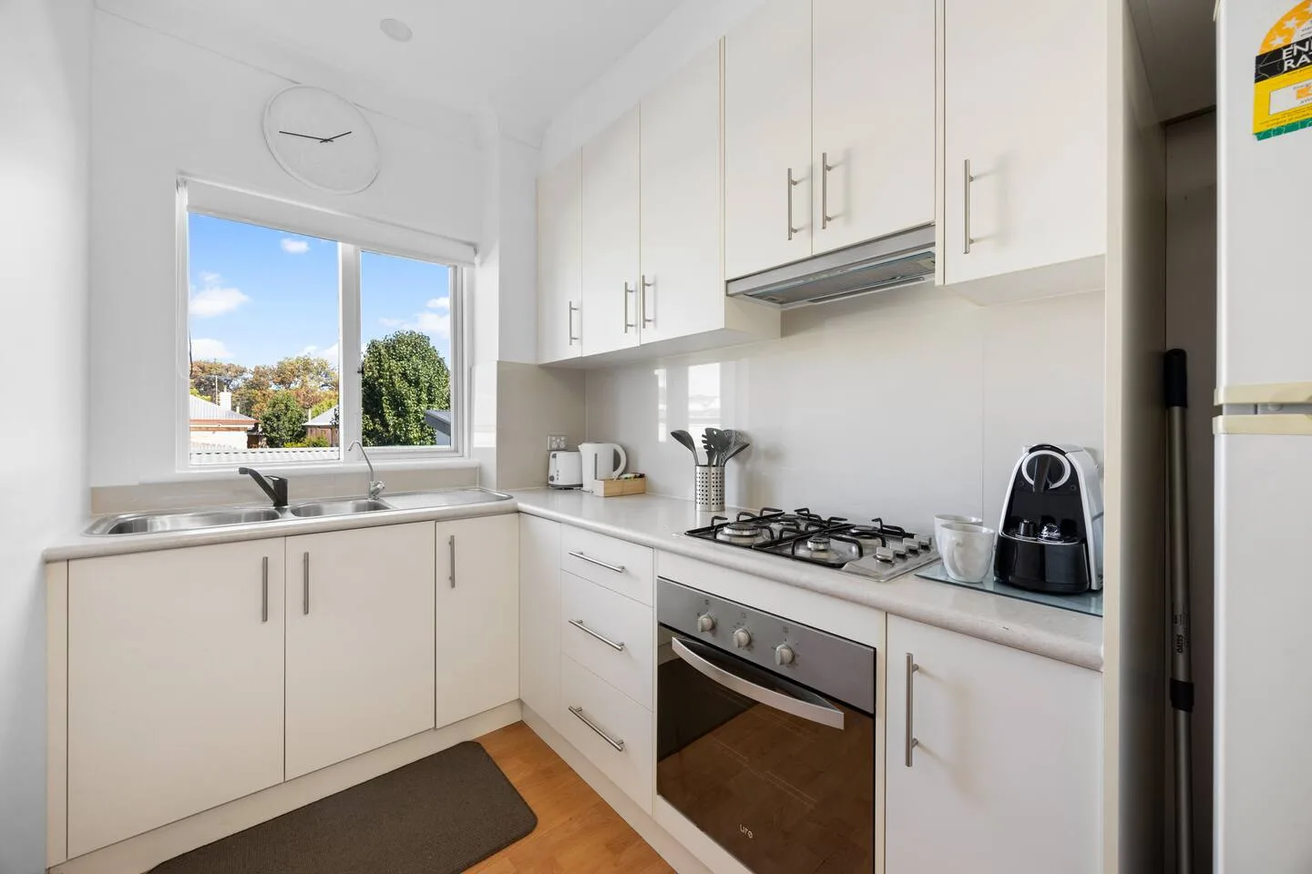 A bright kitchen with white cabinets, a window, and a gas cooktop.