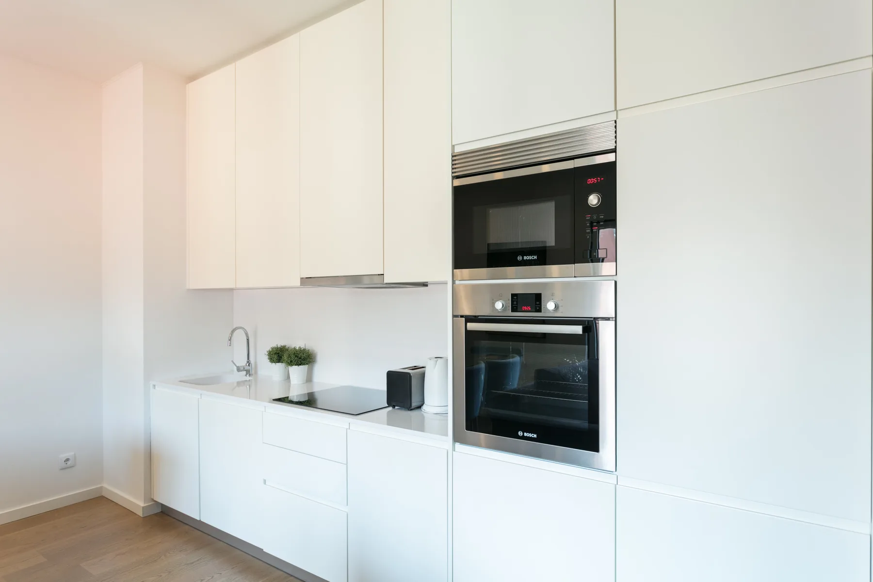 A bright kitchen with white cabinets, a sink, and built-in appliances.
