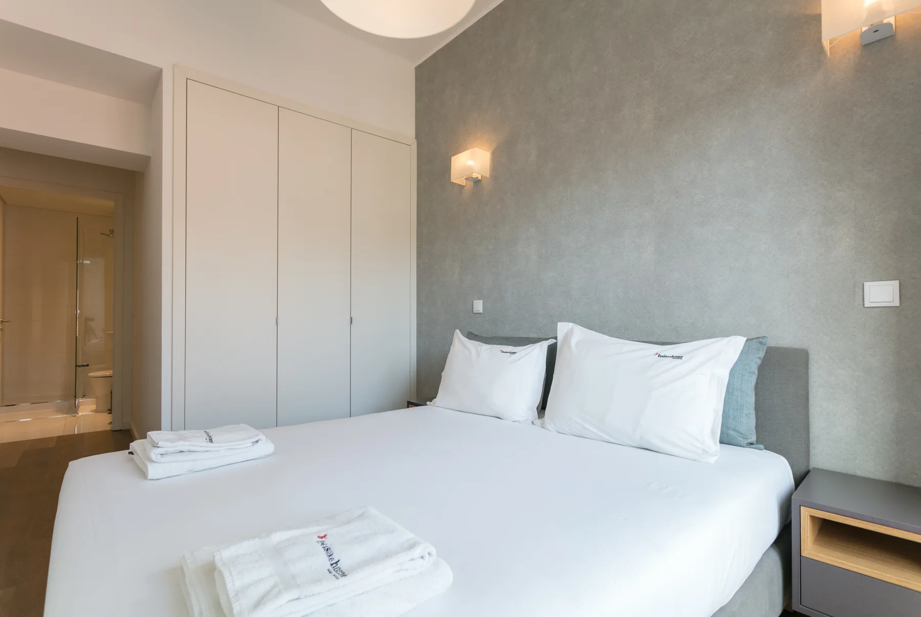 A bedroom with a neatly made bed and folded towels.