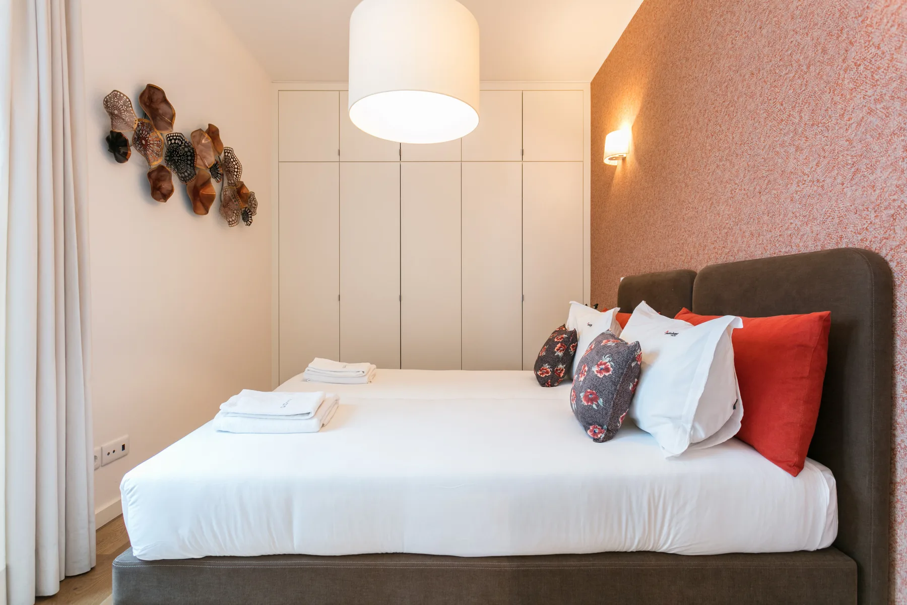 A bedroom with a neatly made bed and colorful pillows.