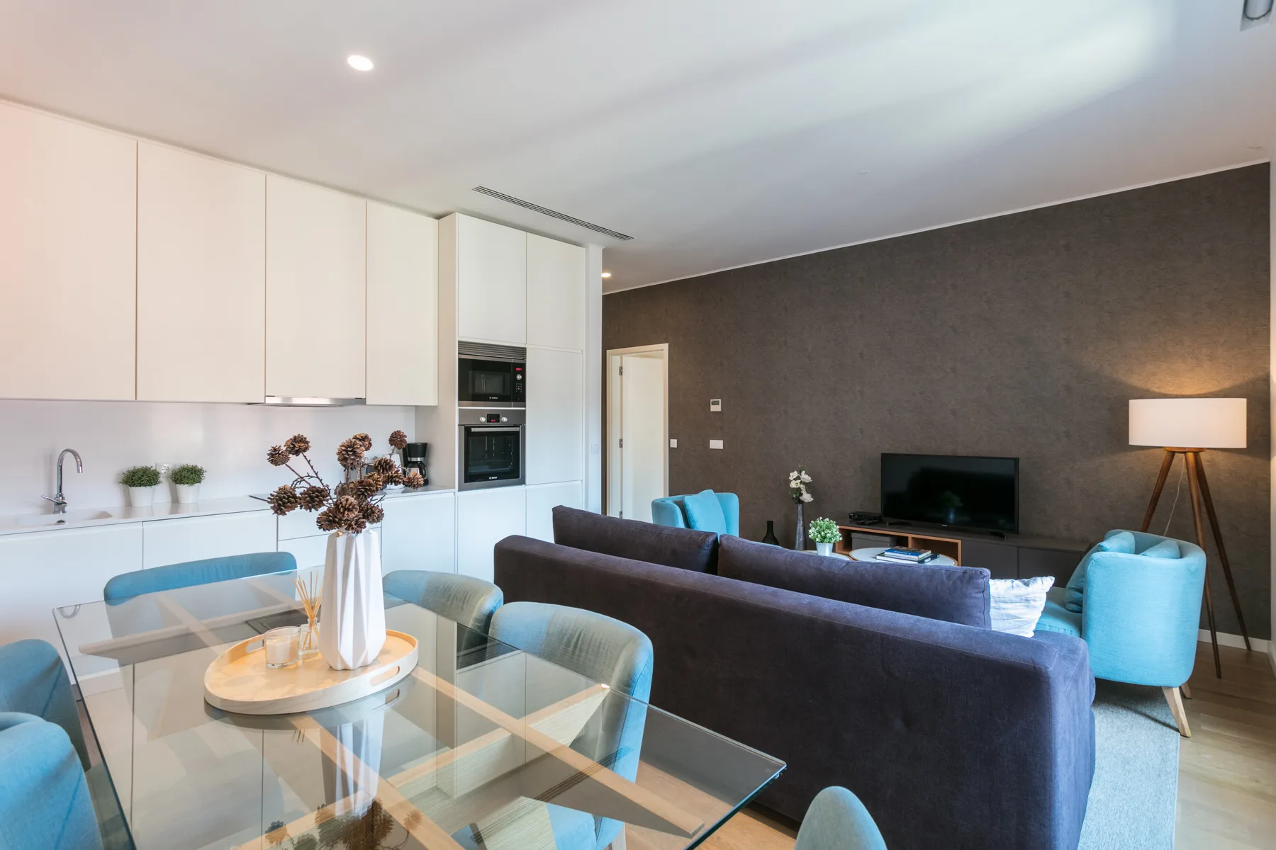 A modern living and dining area with blue seating and a glass dining table.
