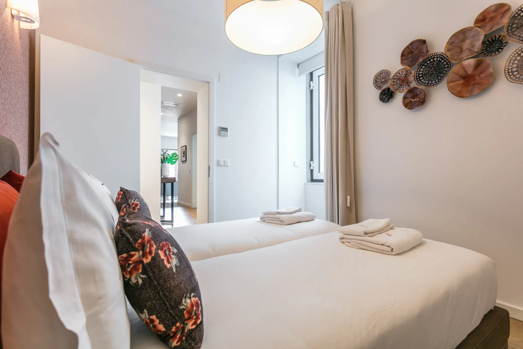 A bedroom with white bedding and decorative wall art.