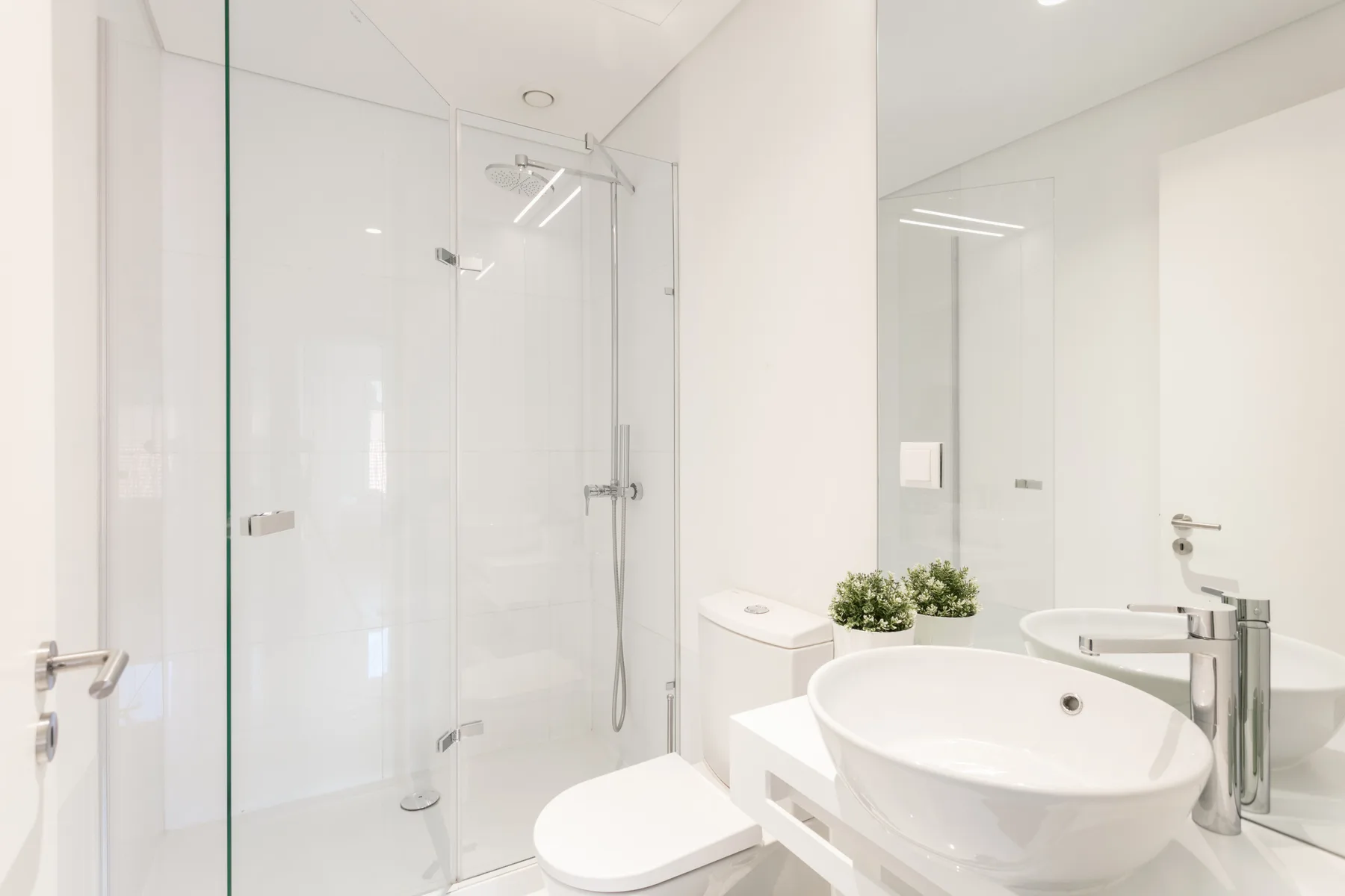 A bright bathroom with a glass shower, toilet, and sink.