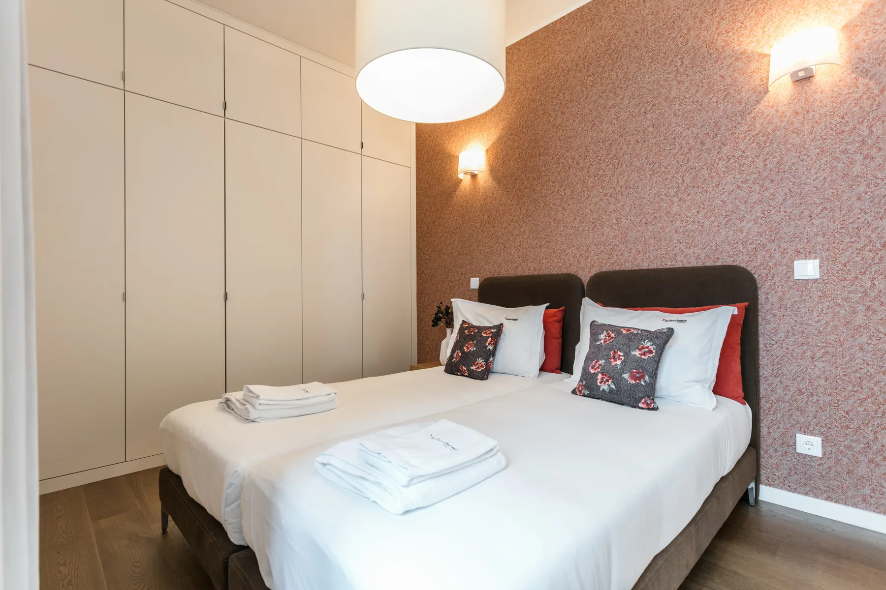 A bedroom with a double bed, white linens, and built-in wardrobes.