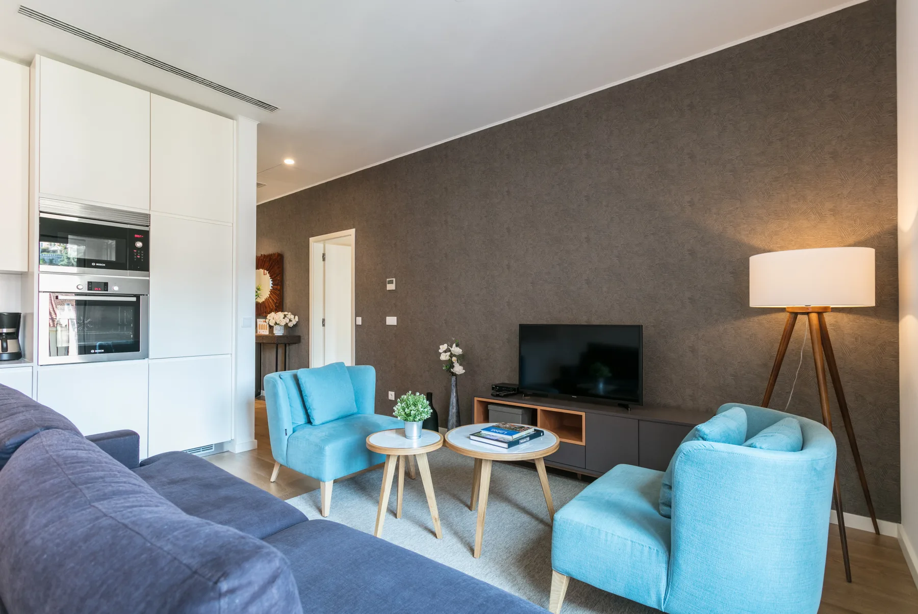 A living room with blue seating, a television, and a floor lamp.