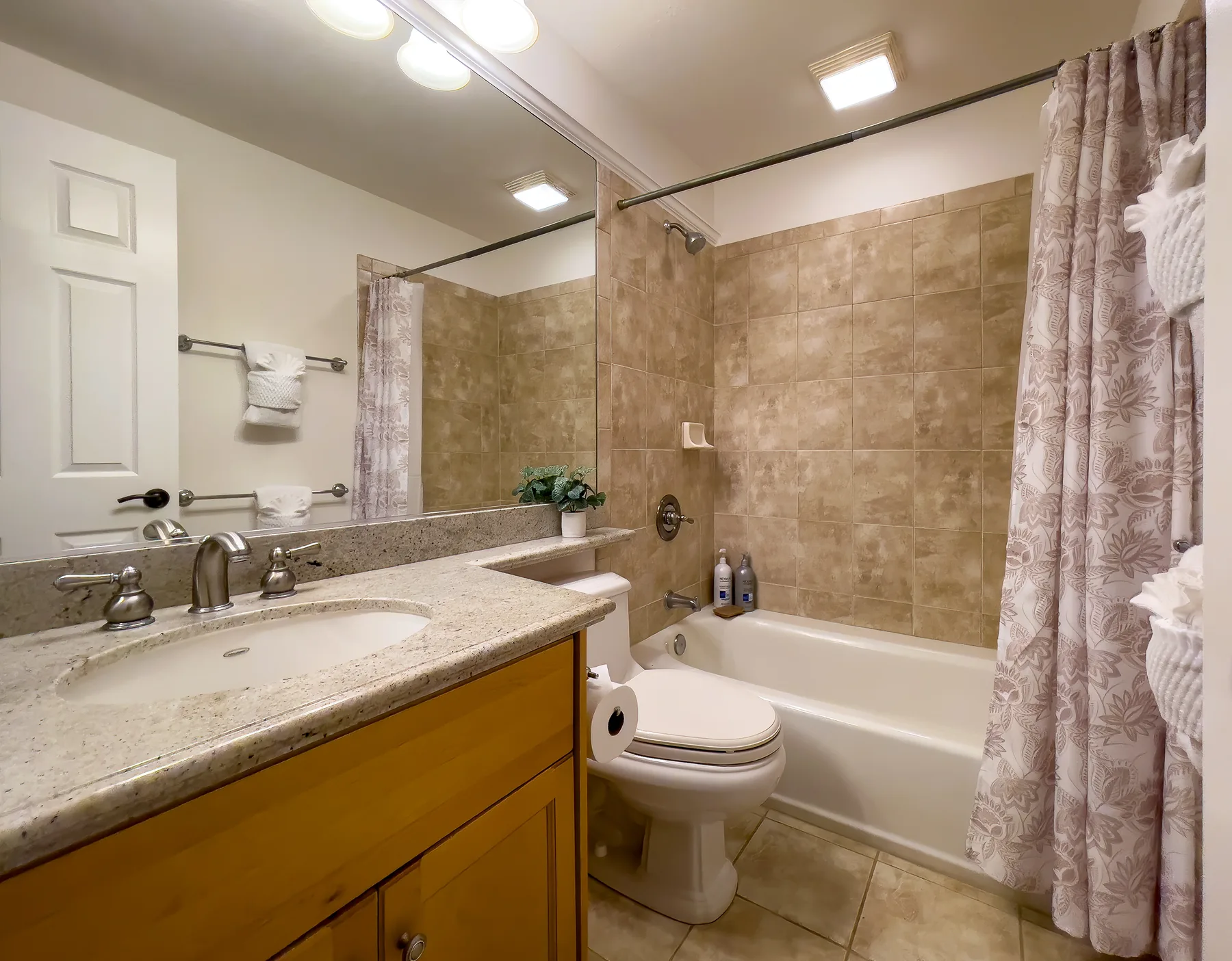 Un baño con lavabo, inodoro y bañera detrás de una cortina de ducha.