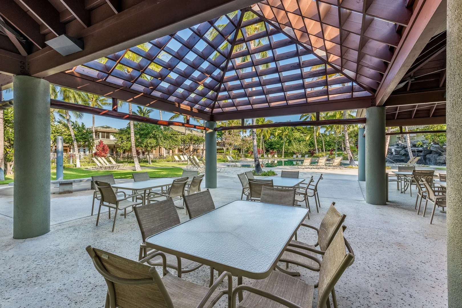 Un comedor exterior cubierto con mesas y asientos bajo un techo elevado.