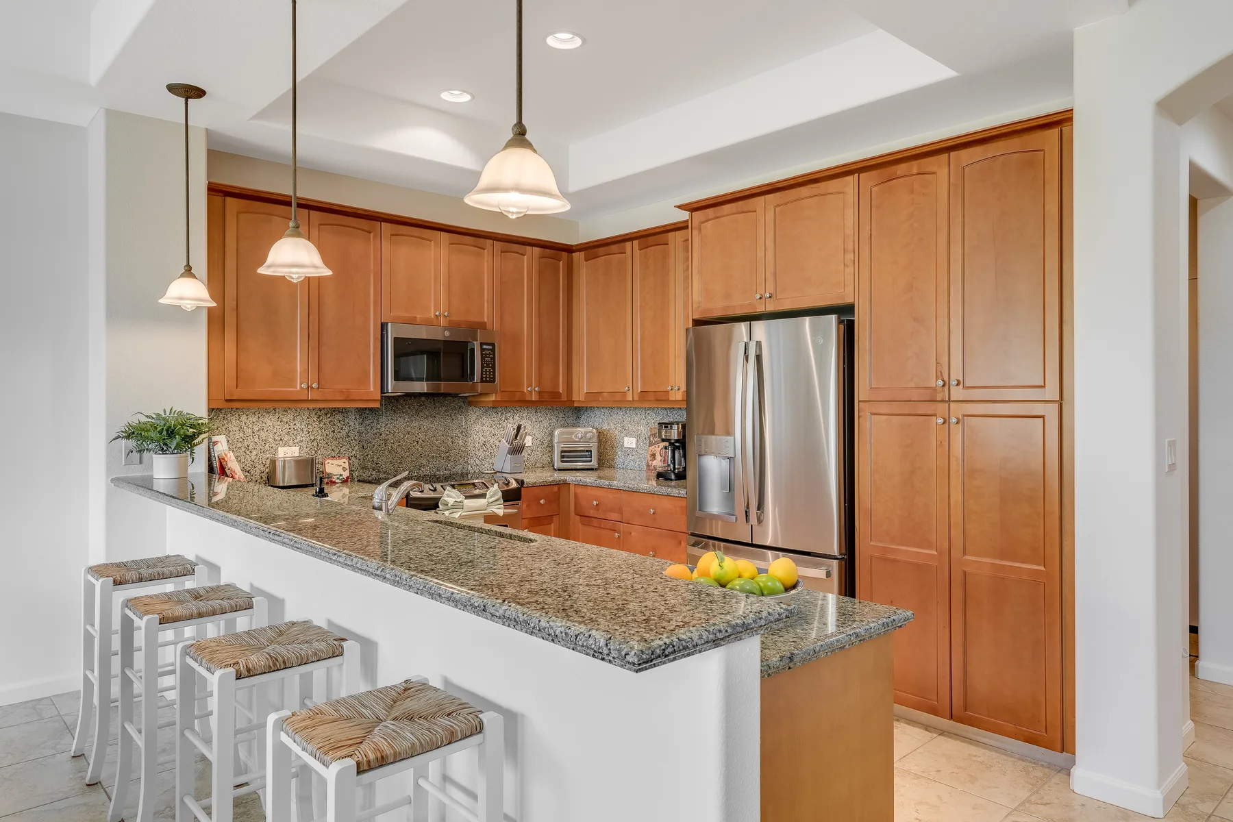 Una cocina con gabinetes de madera, electrodomésticos de acero inoxidable y una isla de piedra.