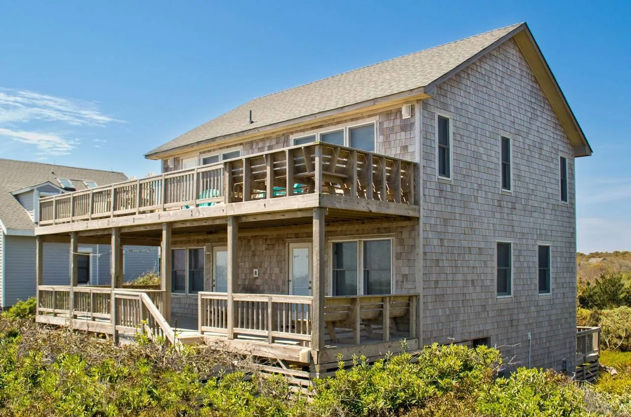 A two-story house with wooden decks and railings.