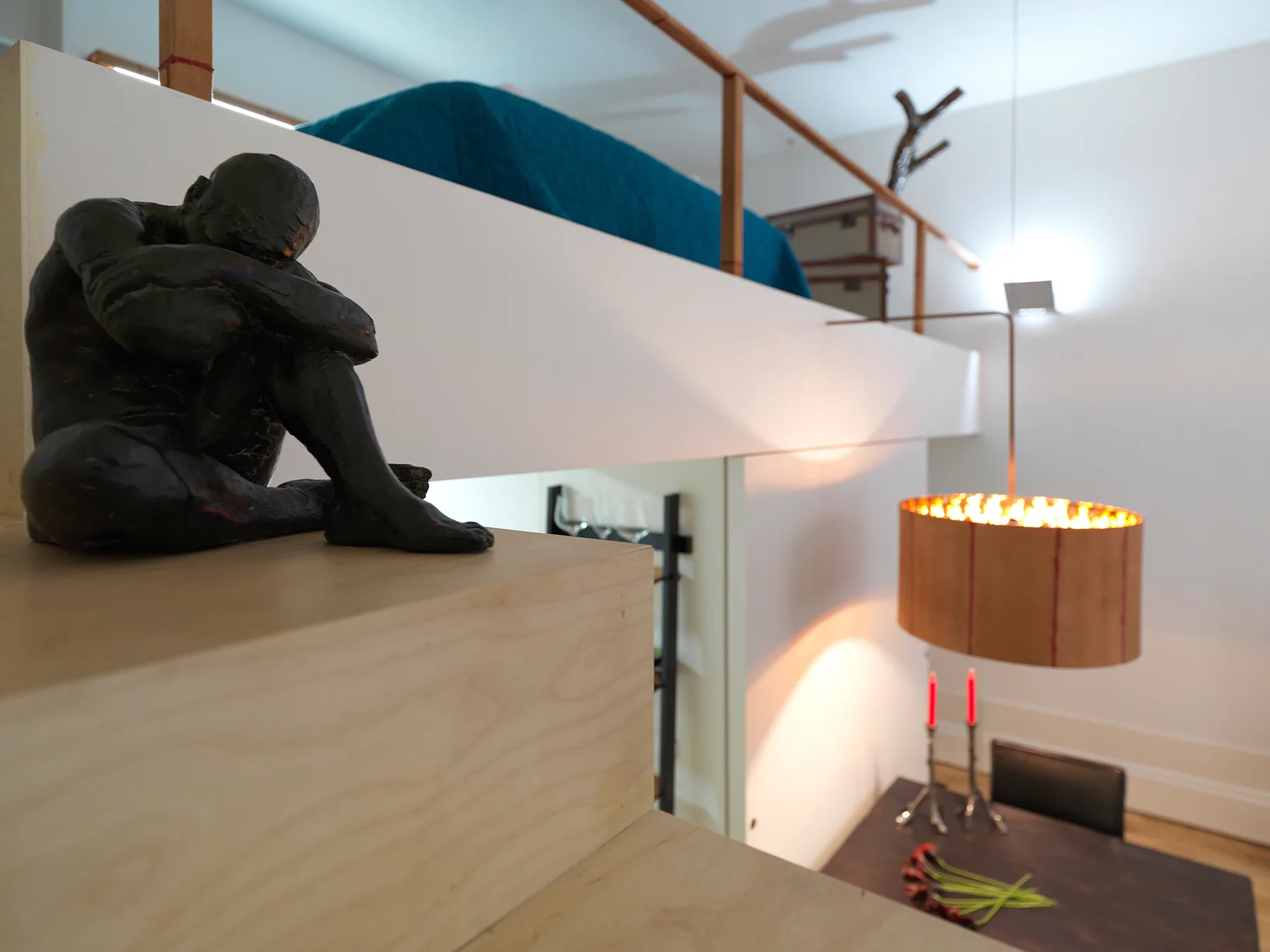 Interior moderno tipo loft con una zona elevada para dormir y una lámpara colgante.