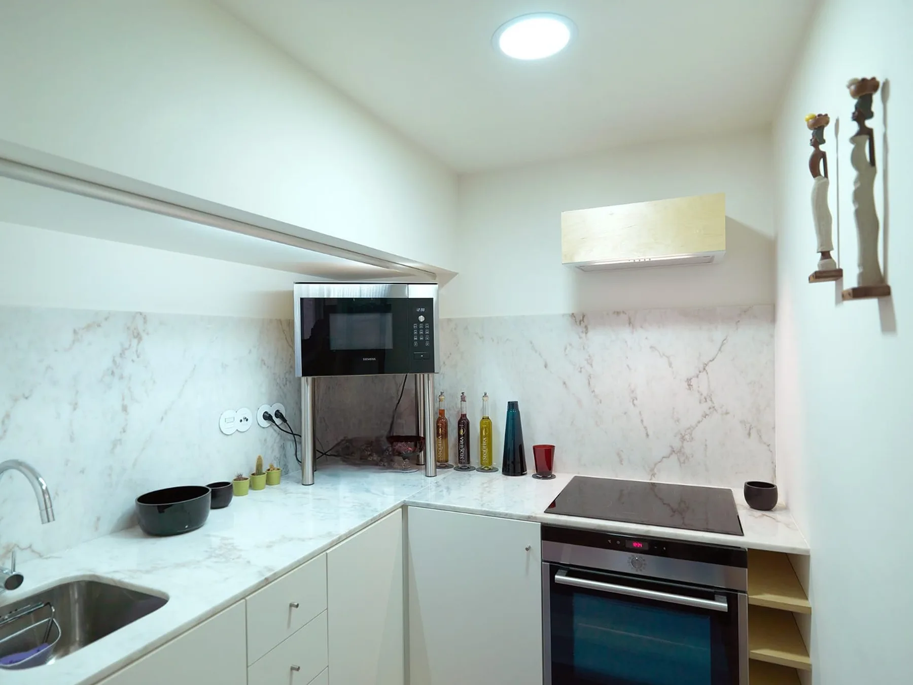 A modern kitchen with white counters, a sink, and built-in appliances.