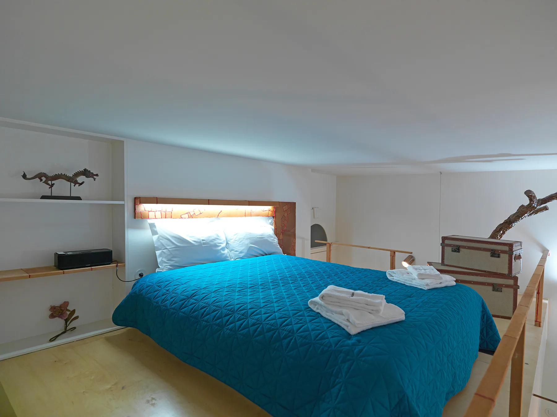 Un dormitorio con una cama cubierta con una colcha azul y toallas dobladas.