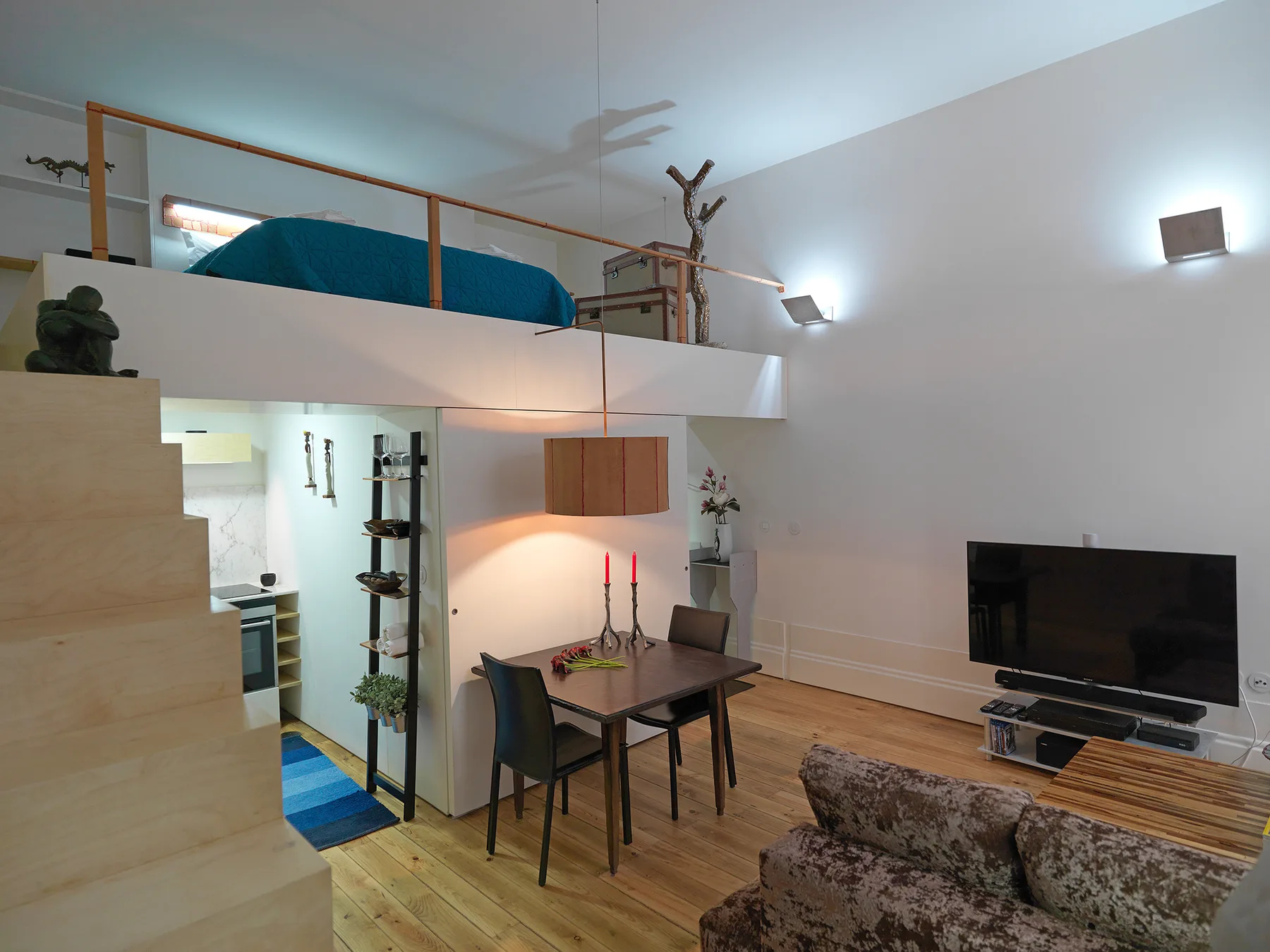 A modern living area with a dining table beneath a raised sleeping space.