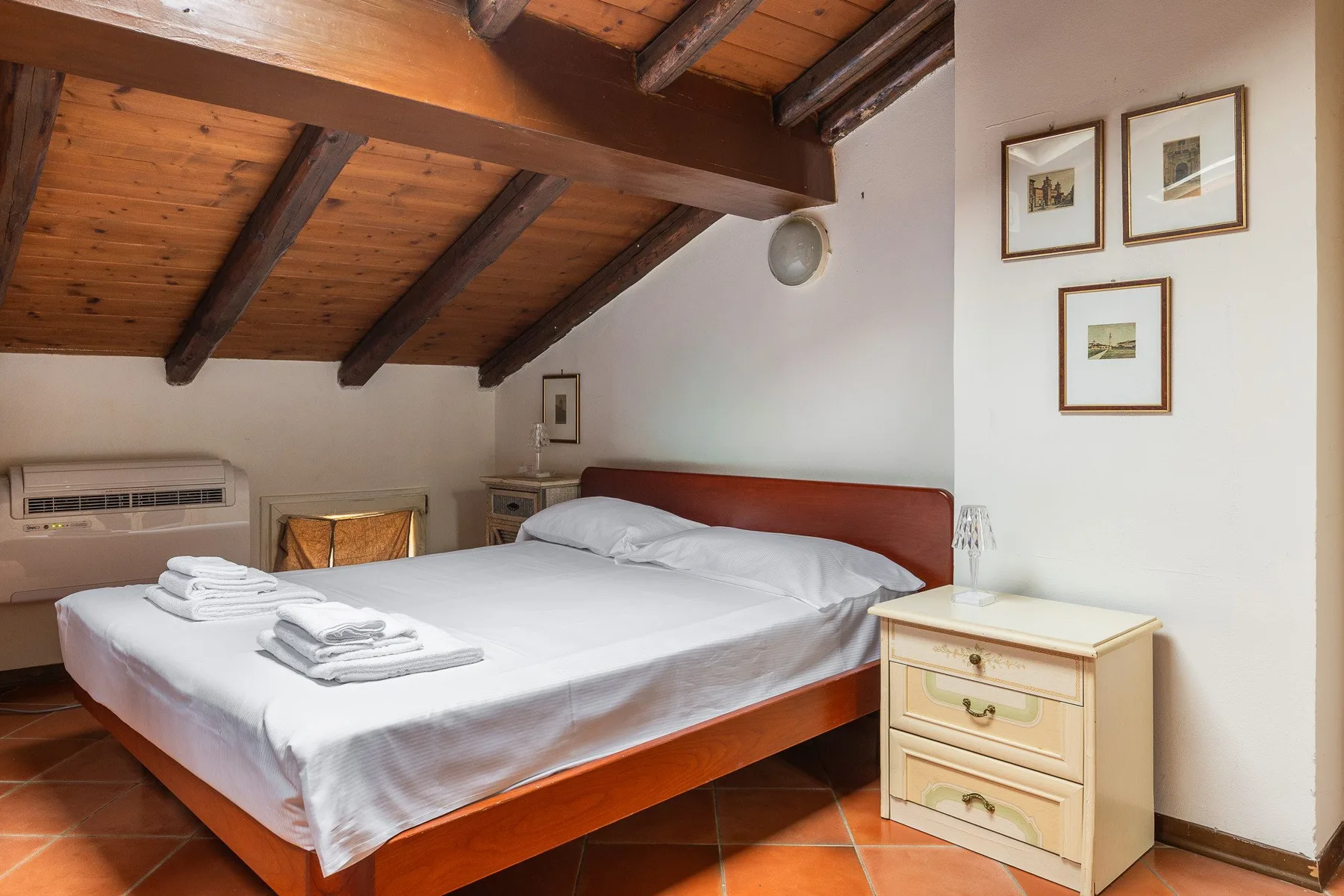 A bedroom with a double bed beneath a sloped wooden ceiling.