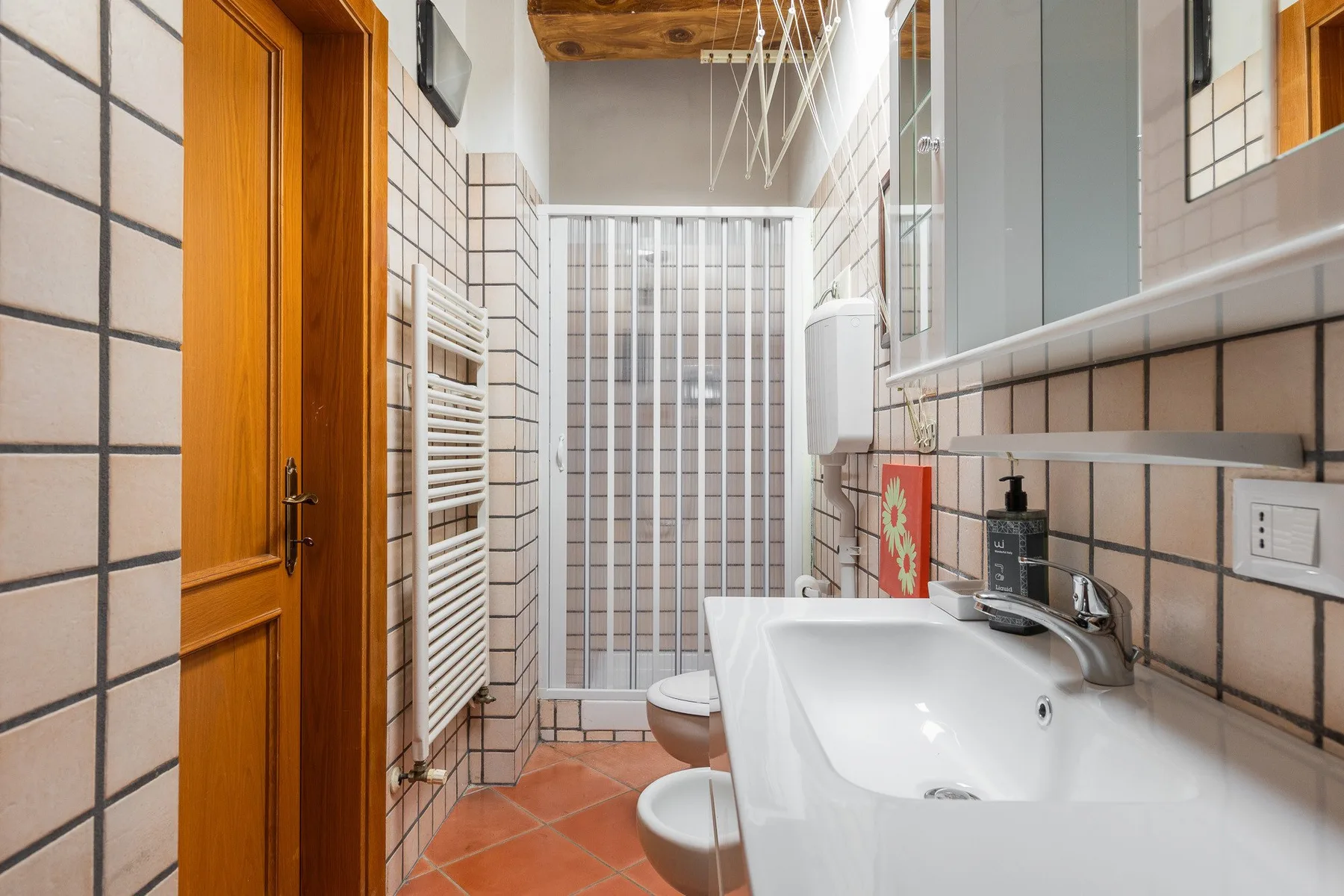 A tiled bathroom with a sink, toilet, and glass shower enclosure.