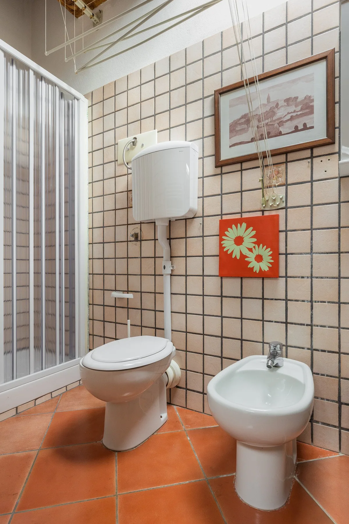 A tiled bathroom with a toilet and bidet beside a shower.