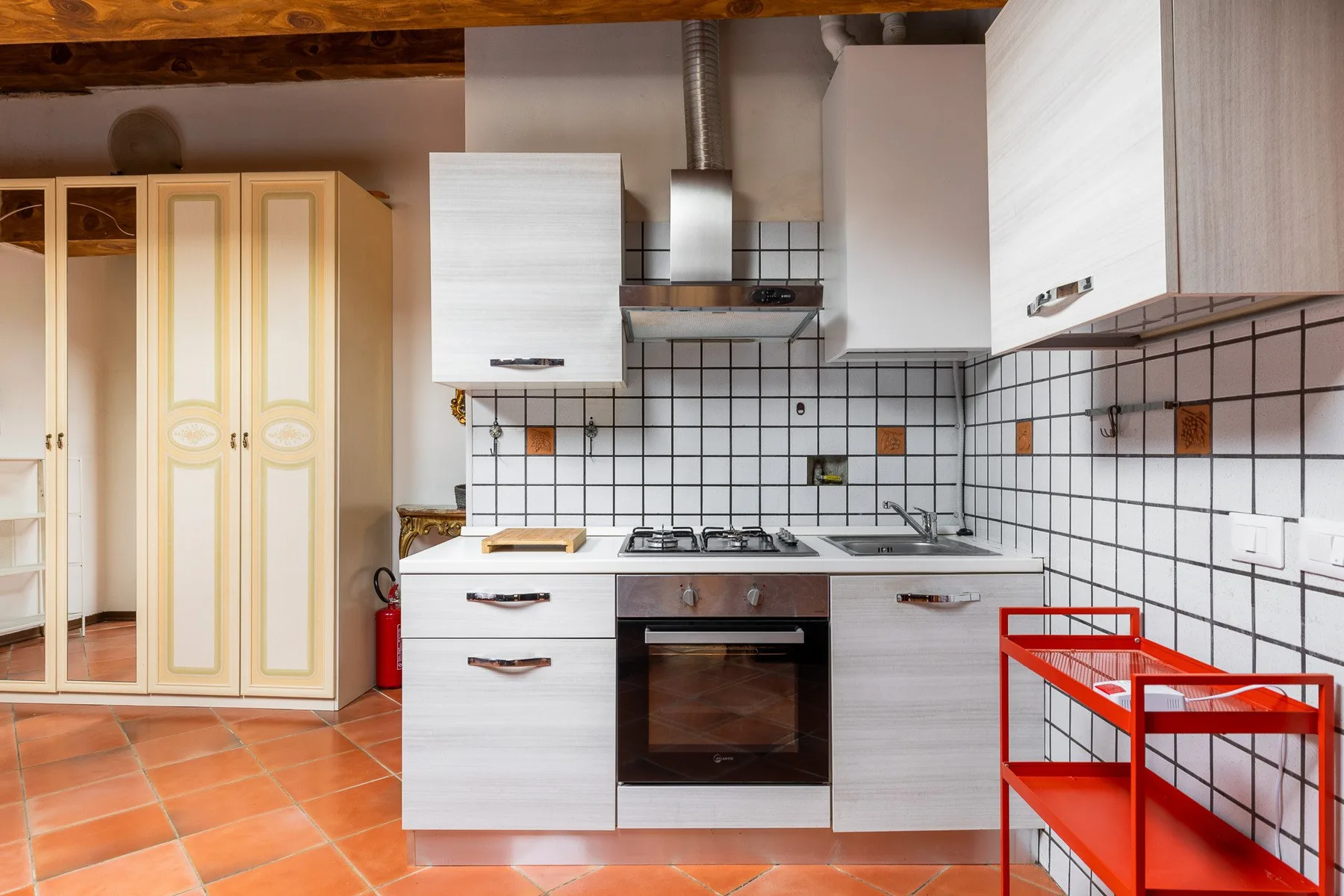 A kitchen with white cabinets, tiled walls, and a built-in oven.