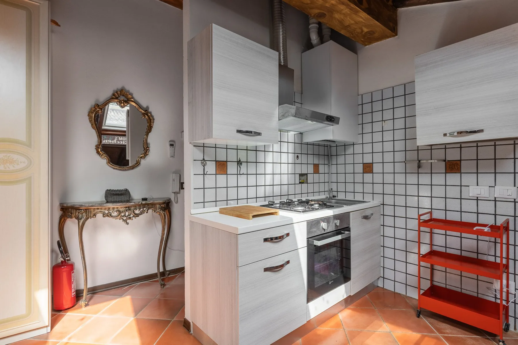 A compact kitchen with white cabinets, tiled walls, and a cooking range.
