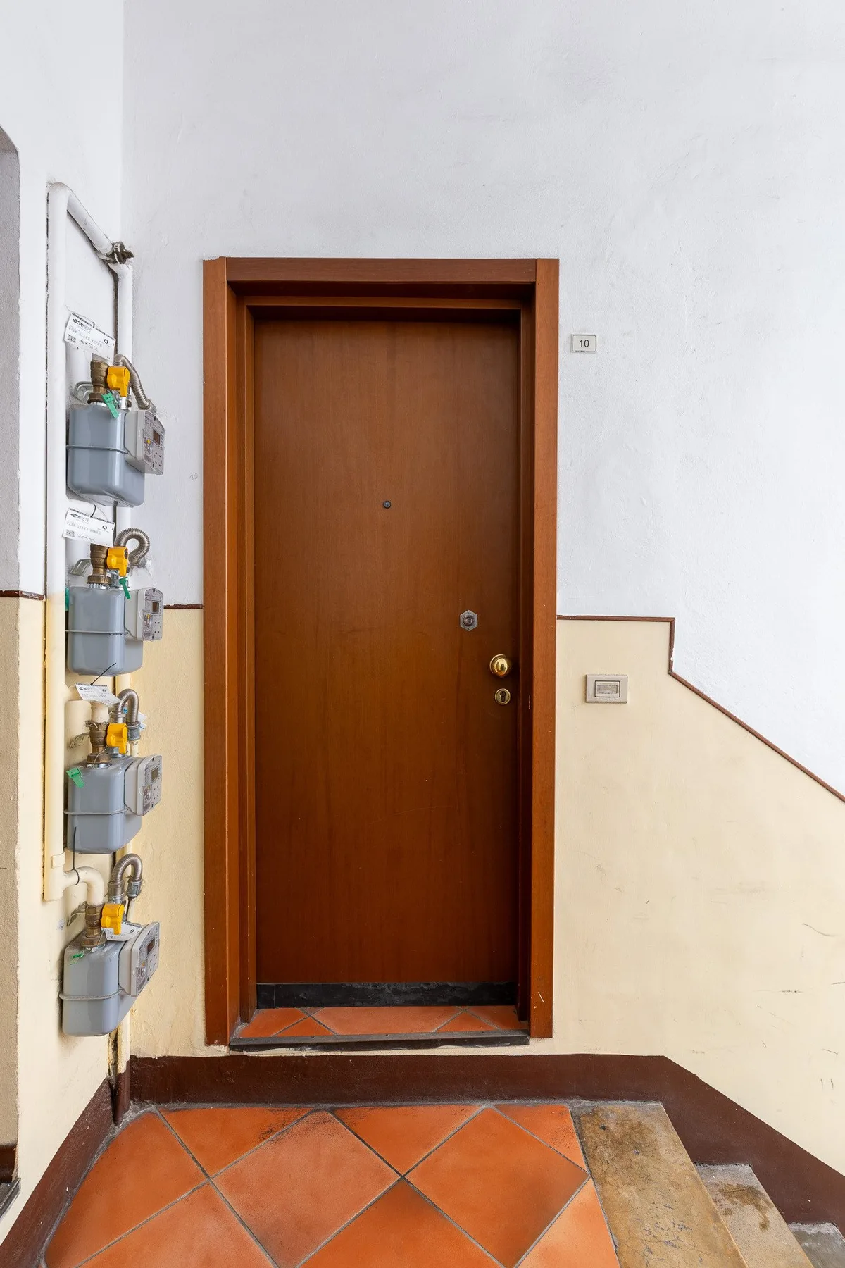 A wooden entrance door opens onto a tiled hallway.