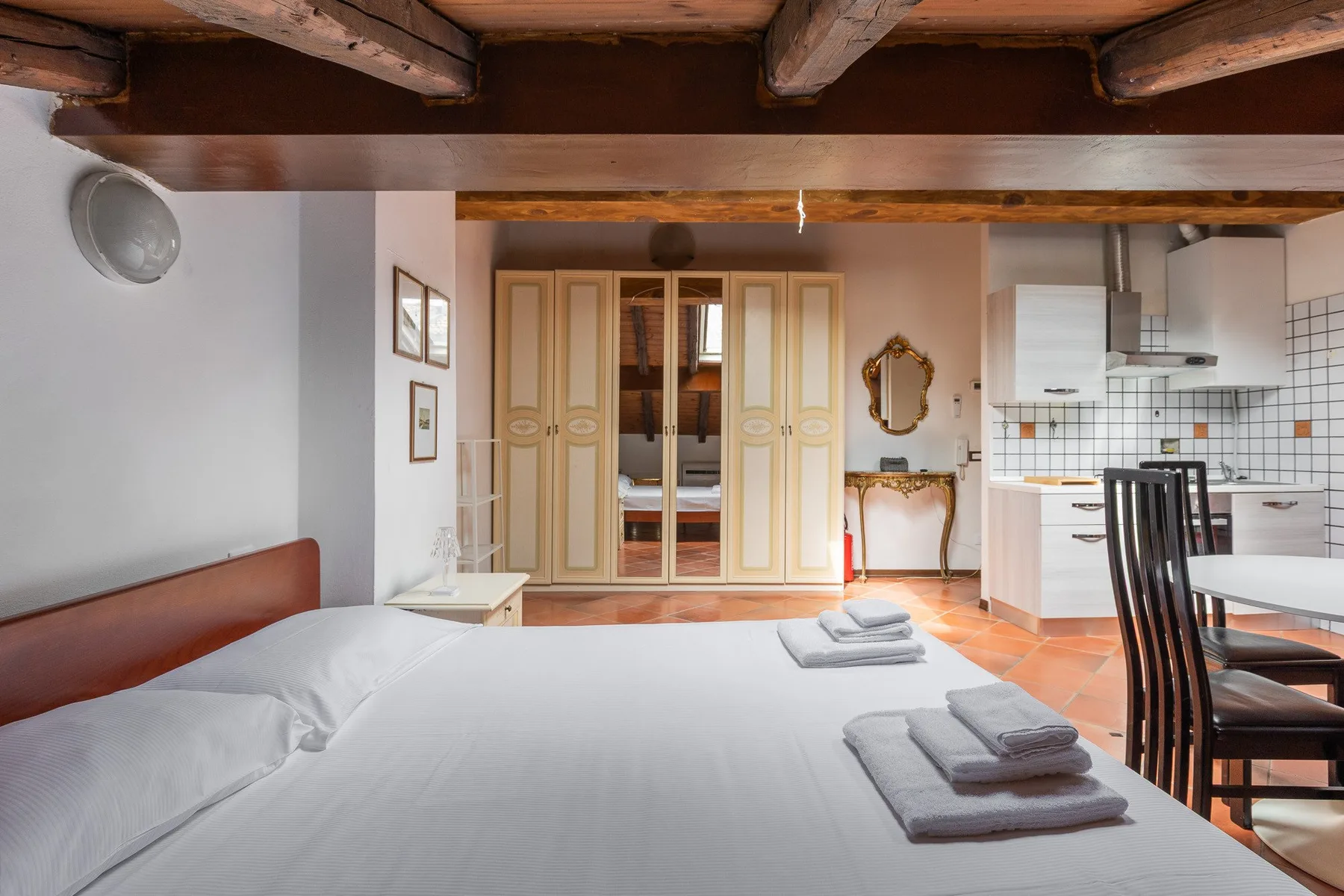 A bedroom with a large bed, wardrobes, and a compact kitchen area.