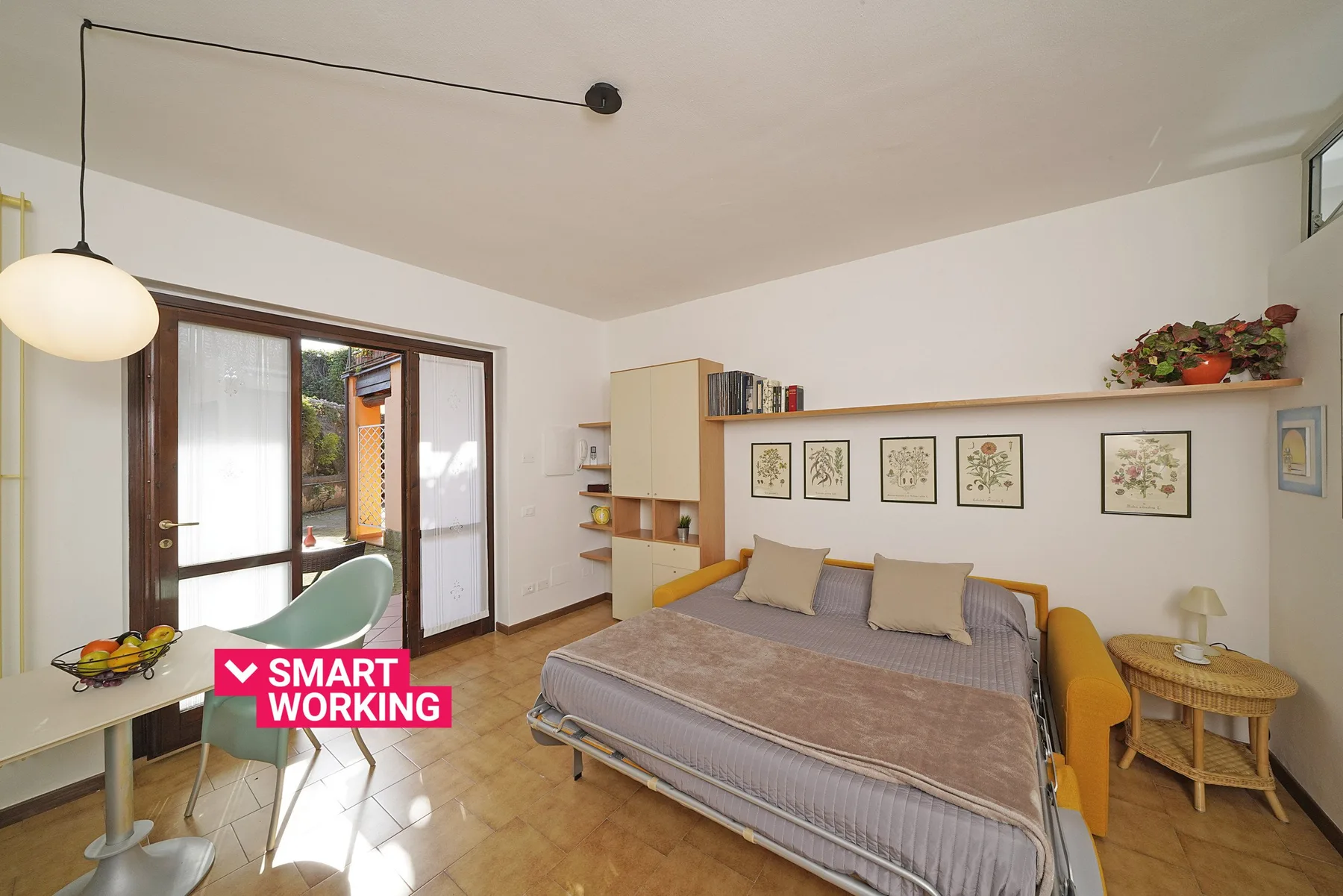 Un dormitorio con una cama doble, un escritorio y una puerta de vidrio que da a un balcón.