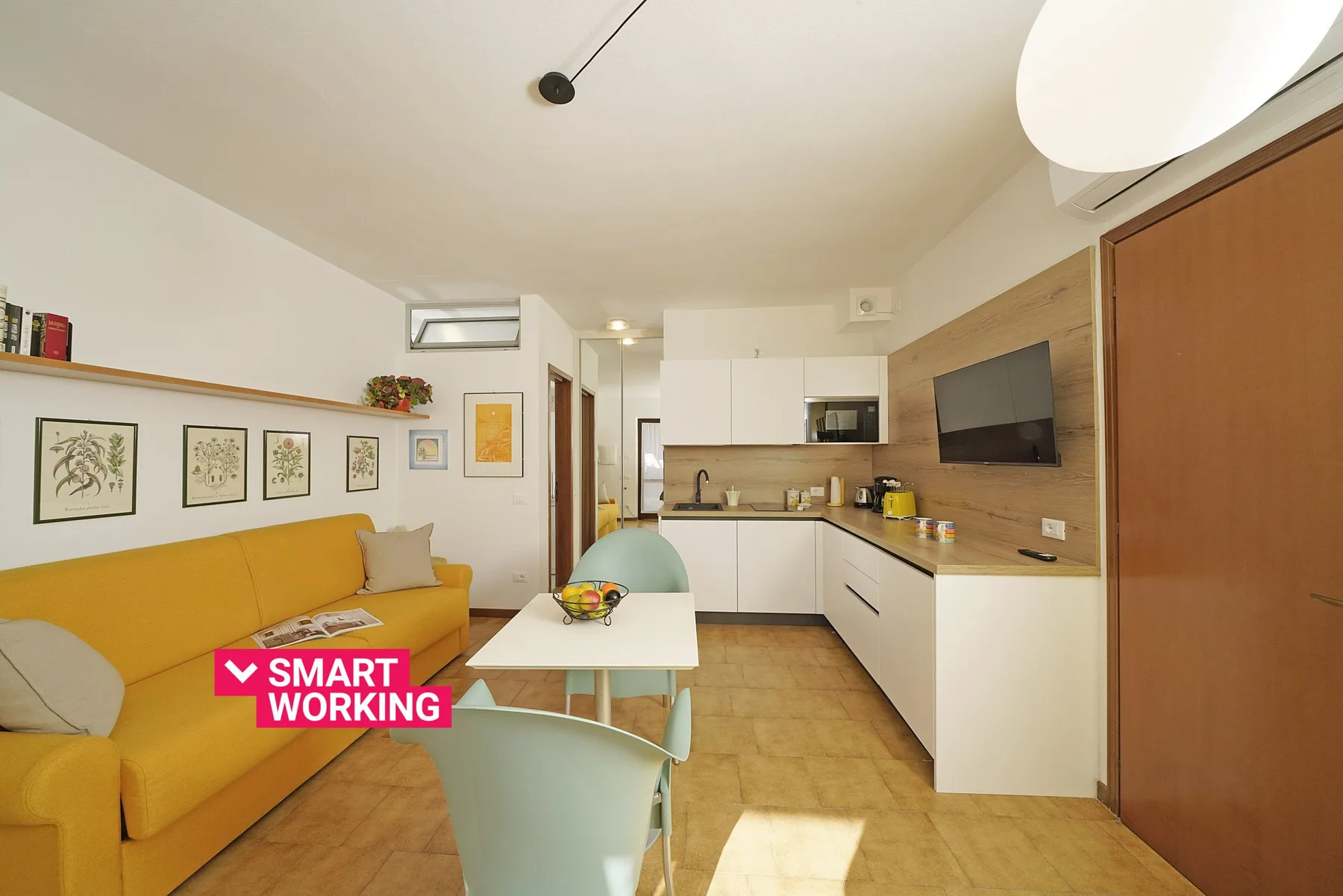 A bright living and kitchen area with a yellow sofa and dining table.