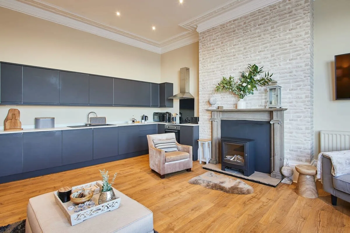 Sala de estar con gabinetes de cocina oscuros y una chimenea.