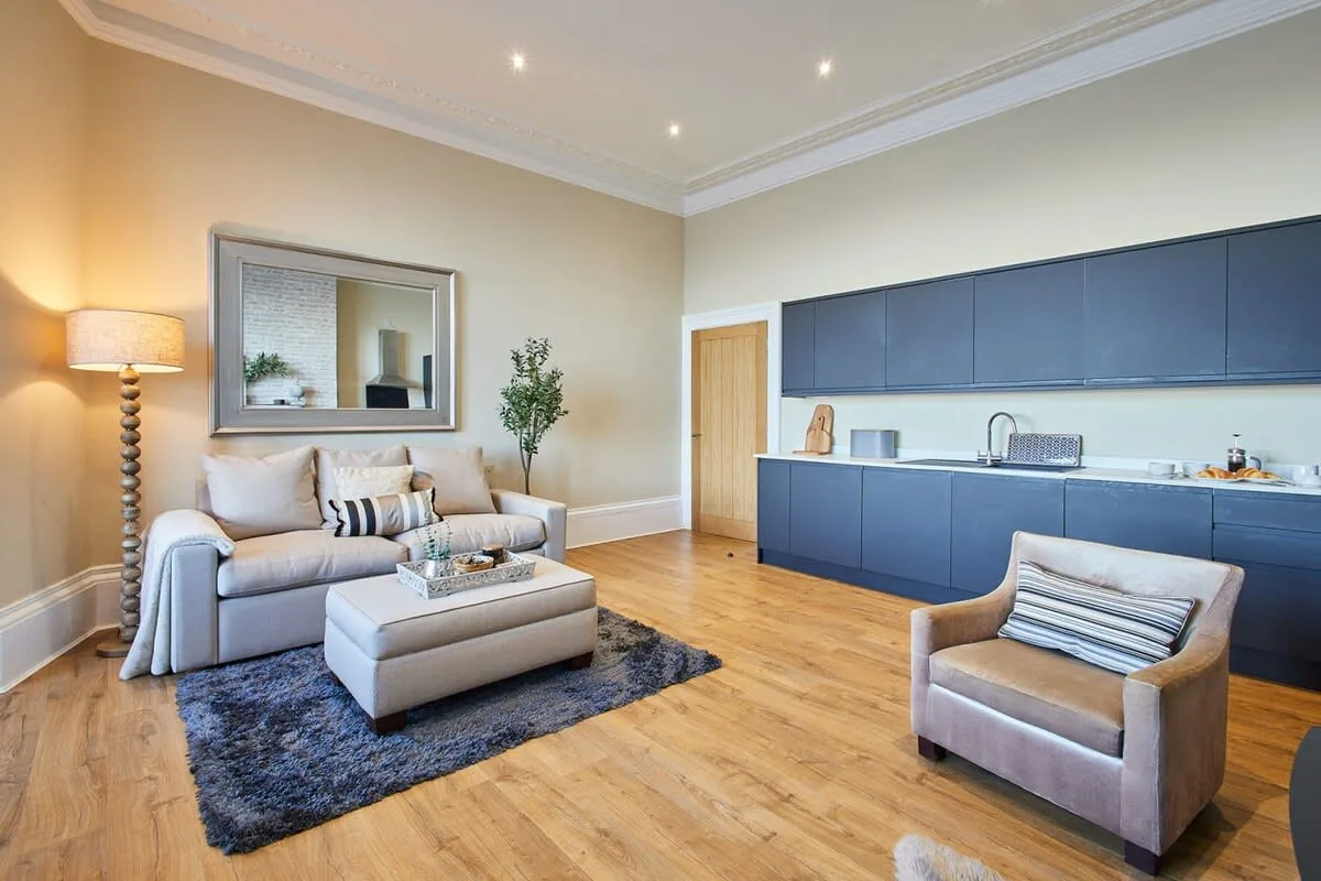 A living room with seating and a kitchen counter along the back wall.