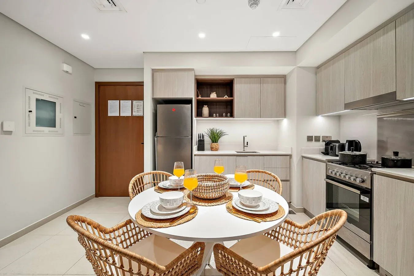 Una cocina luminosa con comedor, mesa puesta y asientos tejidos.