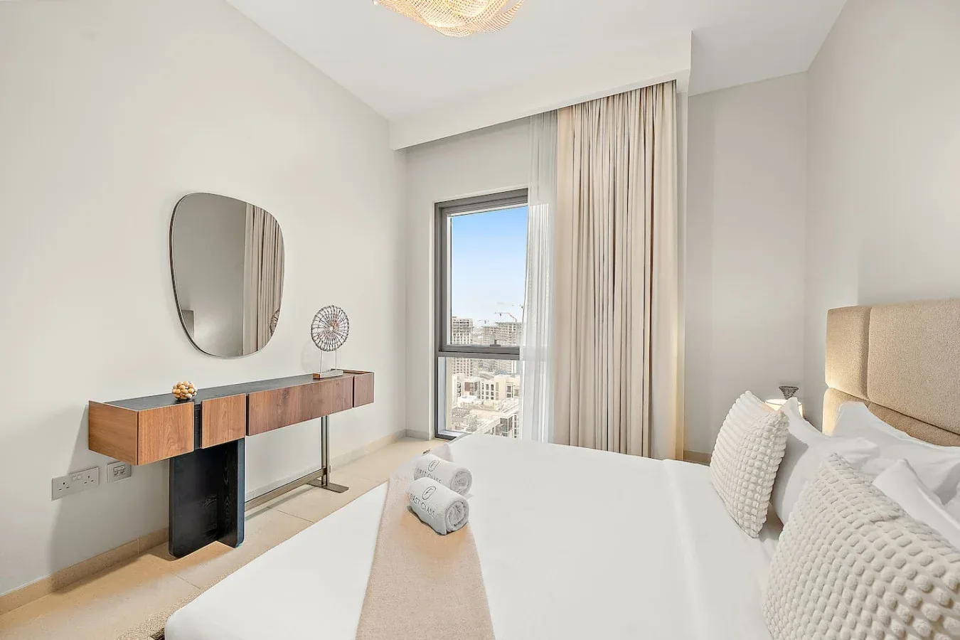 Un dormitorio luminoso con una cama junto a una ventana alta y cortinas.