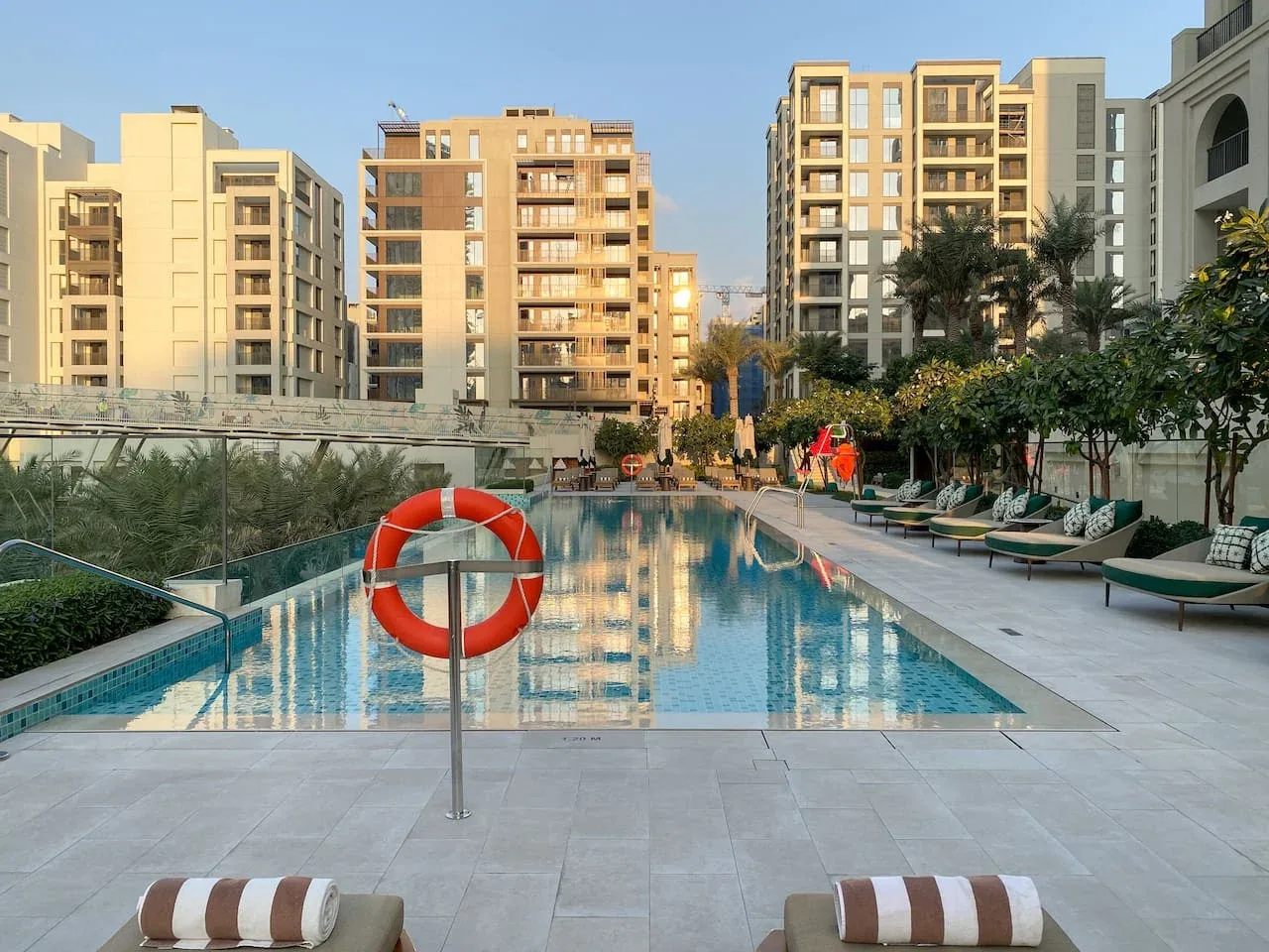 Una piscina al aire libre está rodeada de asientos y edificios de apartamentos.