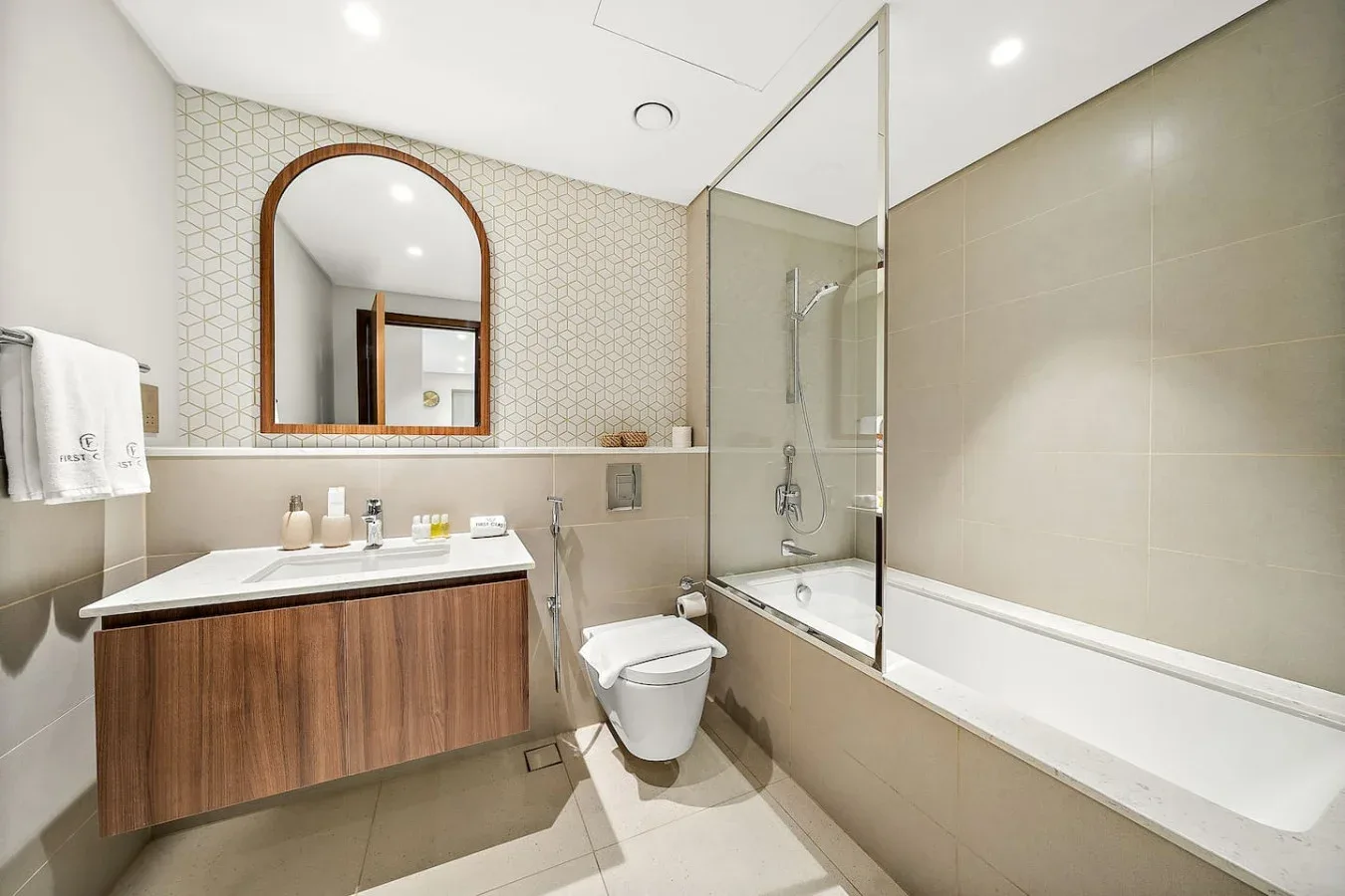 Un baño con lavabo, inodoro y bañera junto a una mampara de ducha de vidrio.